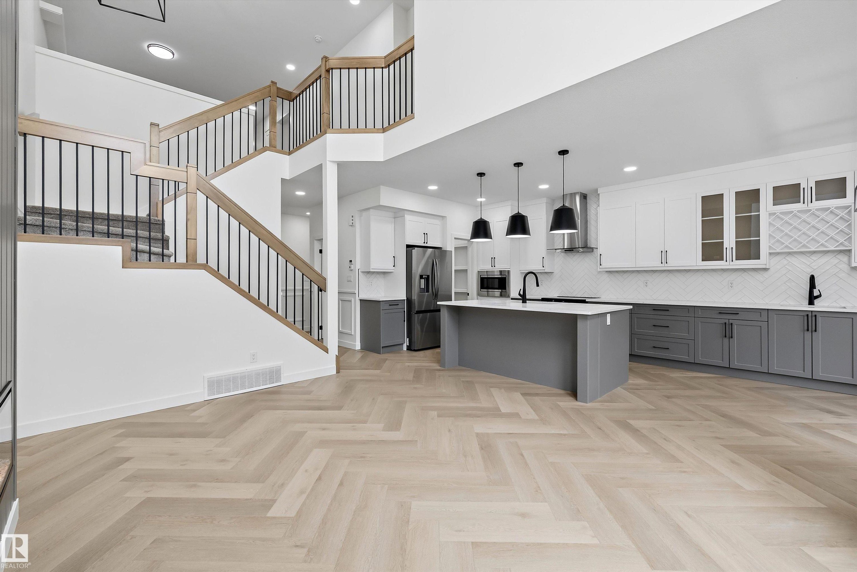 Open-concept kitchen featuring an oversized island, two-tone cabinetry, and stainless steel appliances - 917 Elderberry Landing, Edmonton, AB