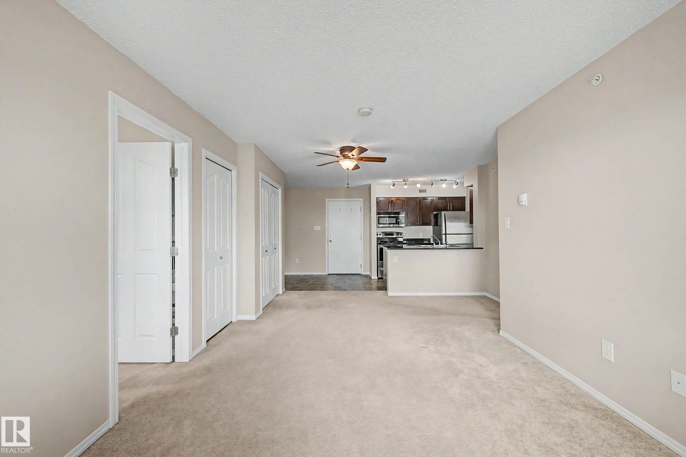 Open concept living area featuring neutral carpeting and a ceiling fan - 404 1080 Mcconachie Boulevard, Edmonton, AB