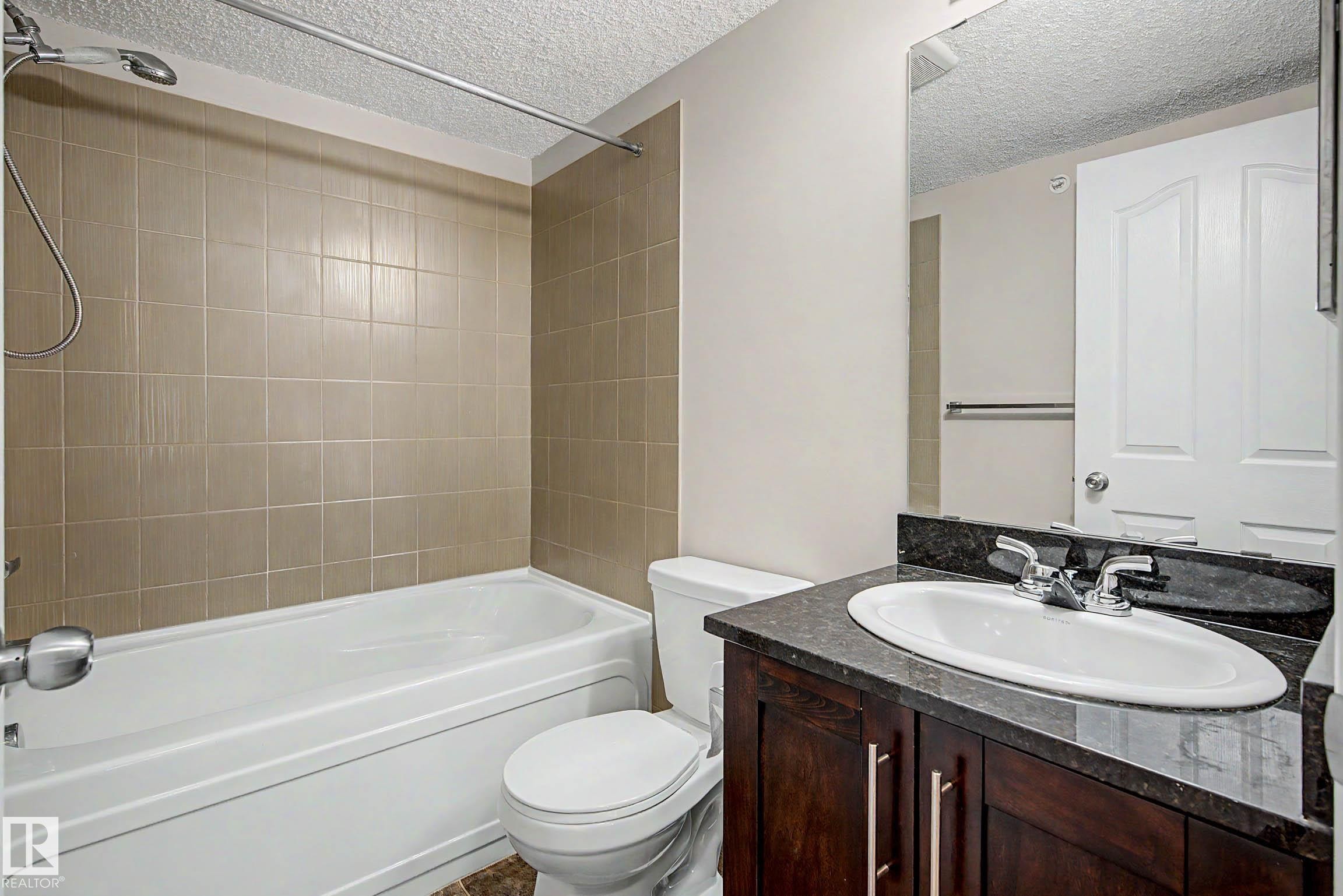 Bathroom featuring a vanity with dark wood-finish cabinetry and a dark countertop - 404 1080 Mcconachie Boulevard, Edmonton, AB