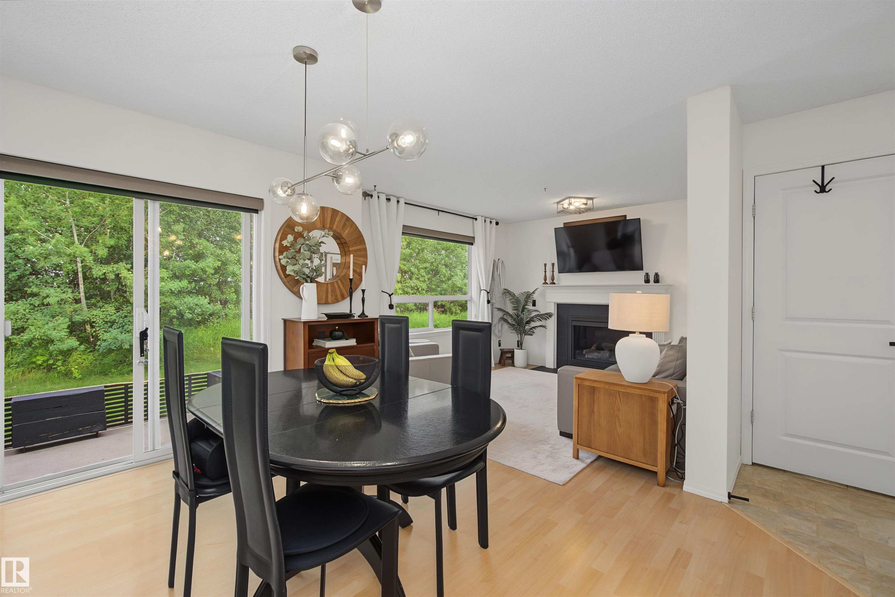 Dining area featuring a contemporary chandelier, light wood-finish flooring, and sliding glass doors leading to an outdoor space - 15 450 Hyndman Crescent, Edmonton, AB