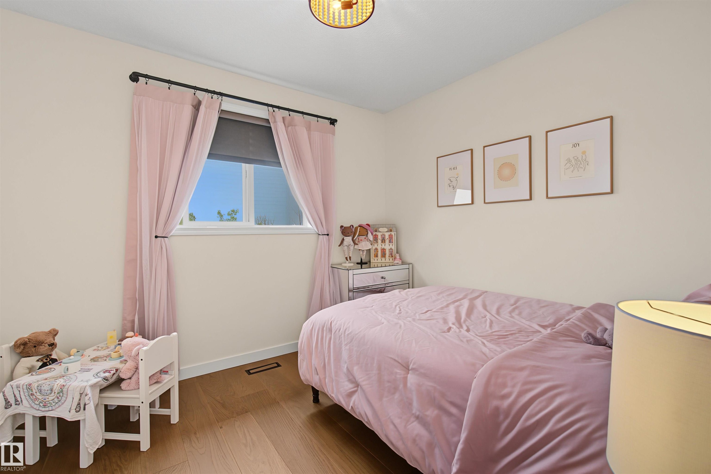 Light-filled room featuring wood-finish flooring, a single window, and a ceiling-mounted light fixture - 15 450 Hyndman Crescent, Edmonton, AB