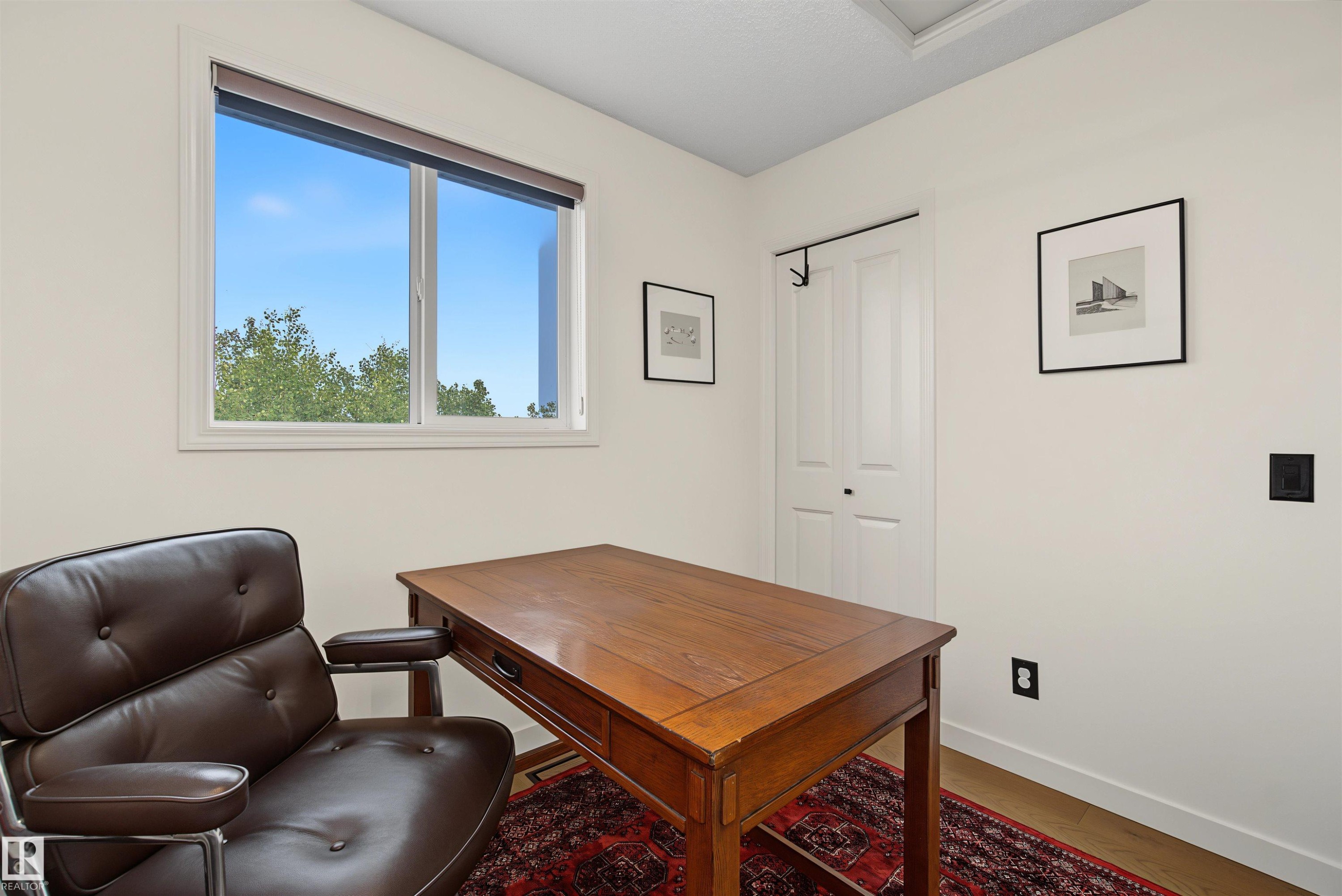 Bright room featuring a large window with roller shade, white bi-fold closet doors, and light wood-finish flooring - 15 450 Hyndman Crescent, Edmonton, AB