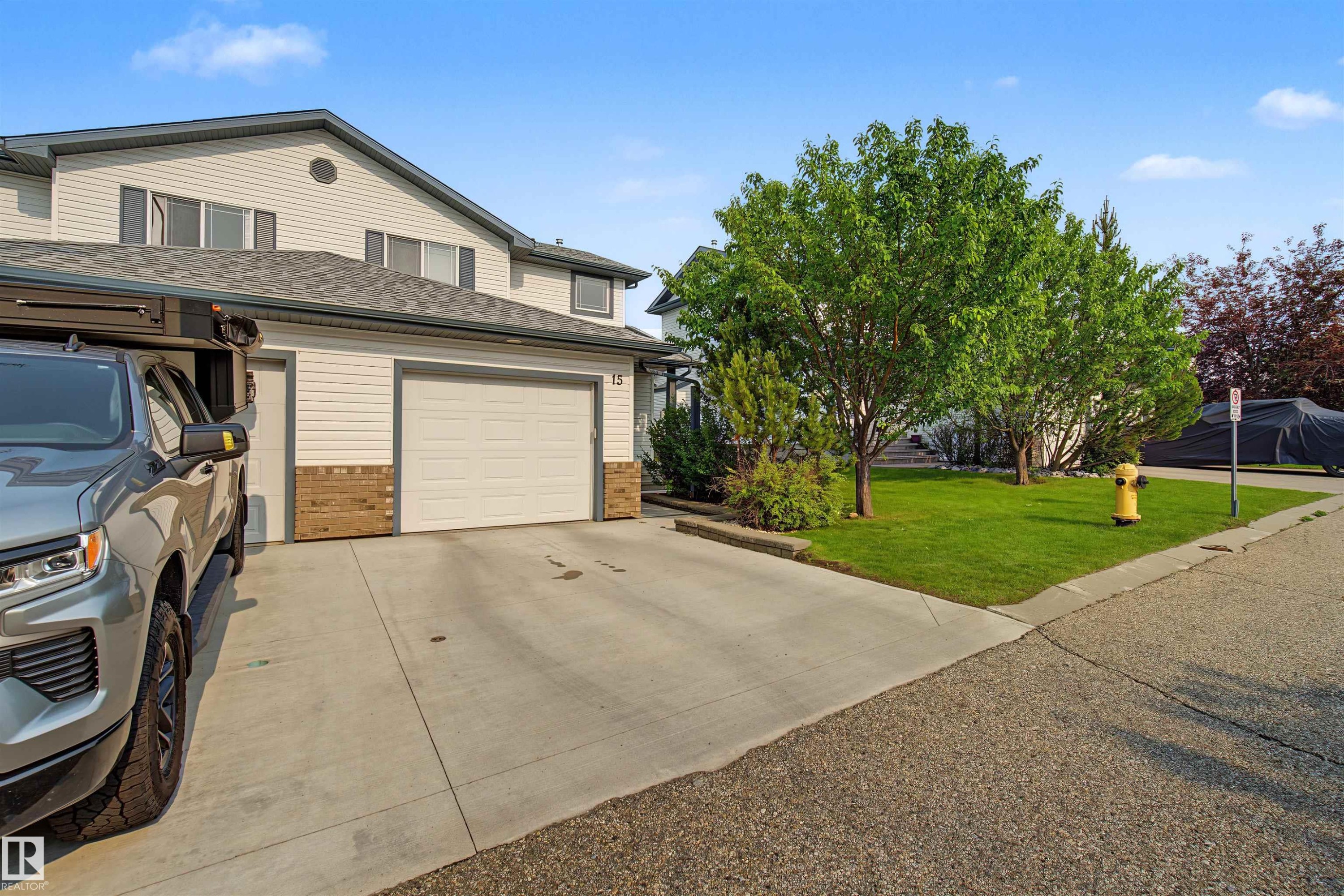 Two-story property featuring light-colored siding, a dark shingle roof, and an attached two-car garage - 15 450 Hyndman Crescent, Edmonton, AB