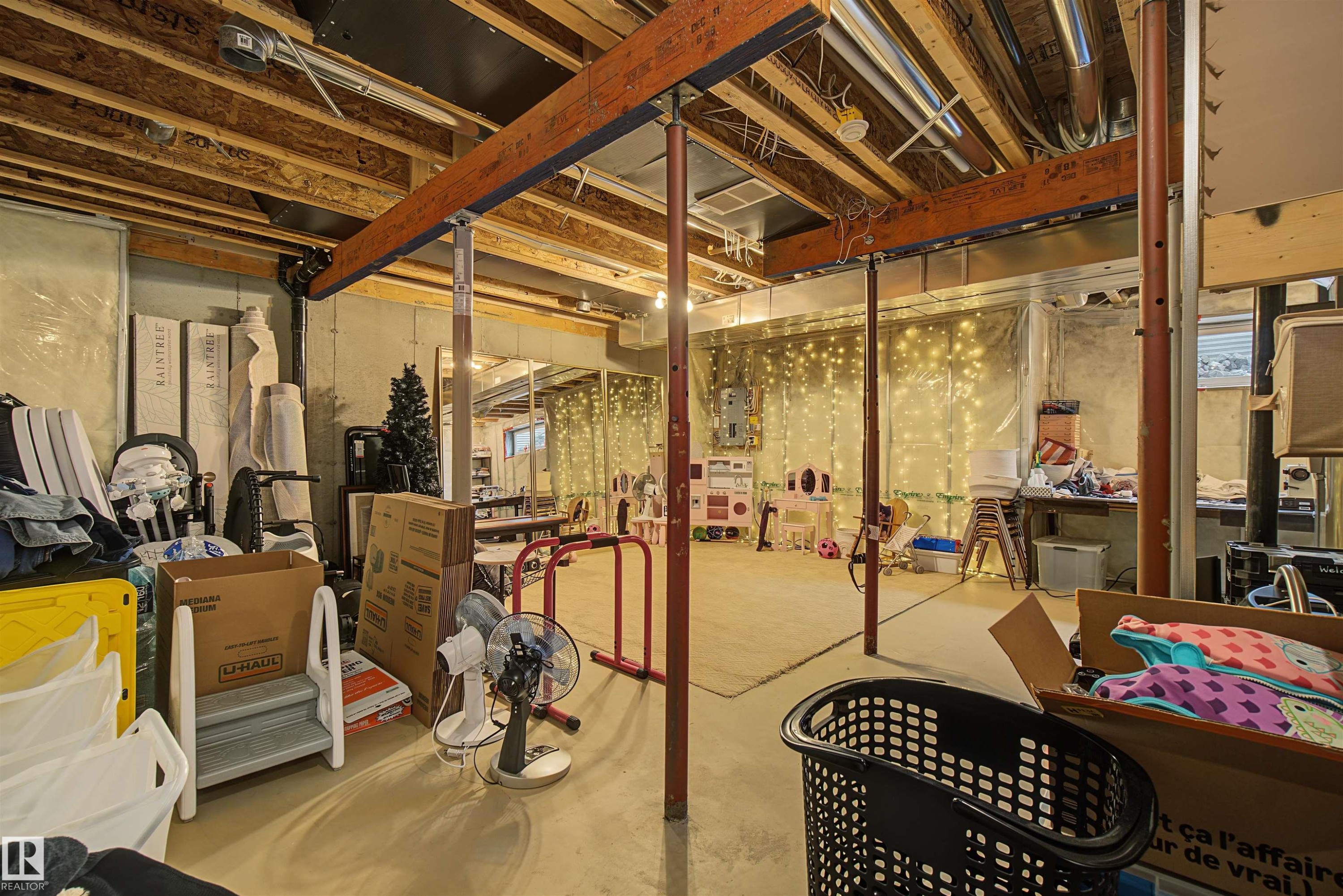 Unfinished basement space with exposed wooden joists and structural beams, concrete flooring, and visible utility infrastructure, offering expansion potential - 15 450 Hyndman Crescent, Edmonton, AB