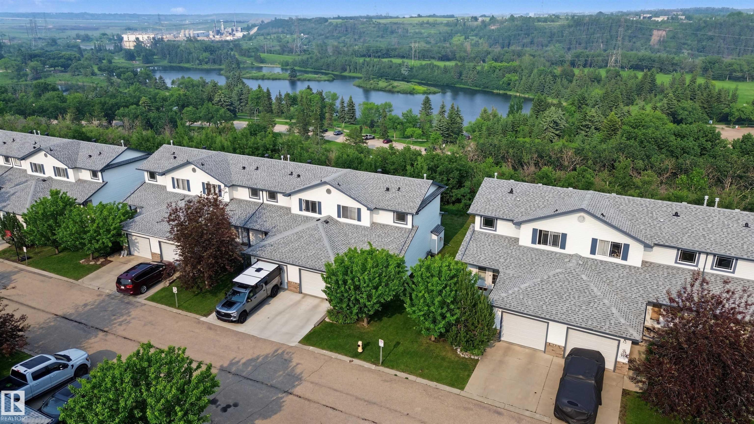 Aerial perspective showcasing a row of townhomes with a natural landscape backdrop - 15 450 Hyndman Crescent, Edmonton, AB