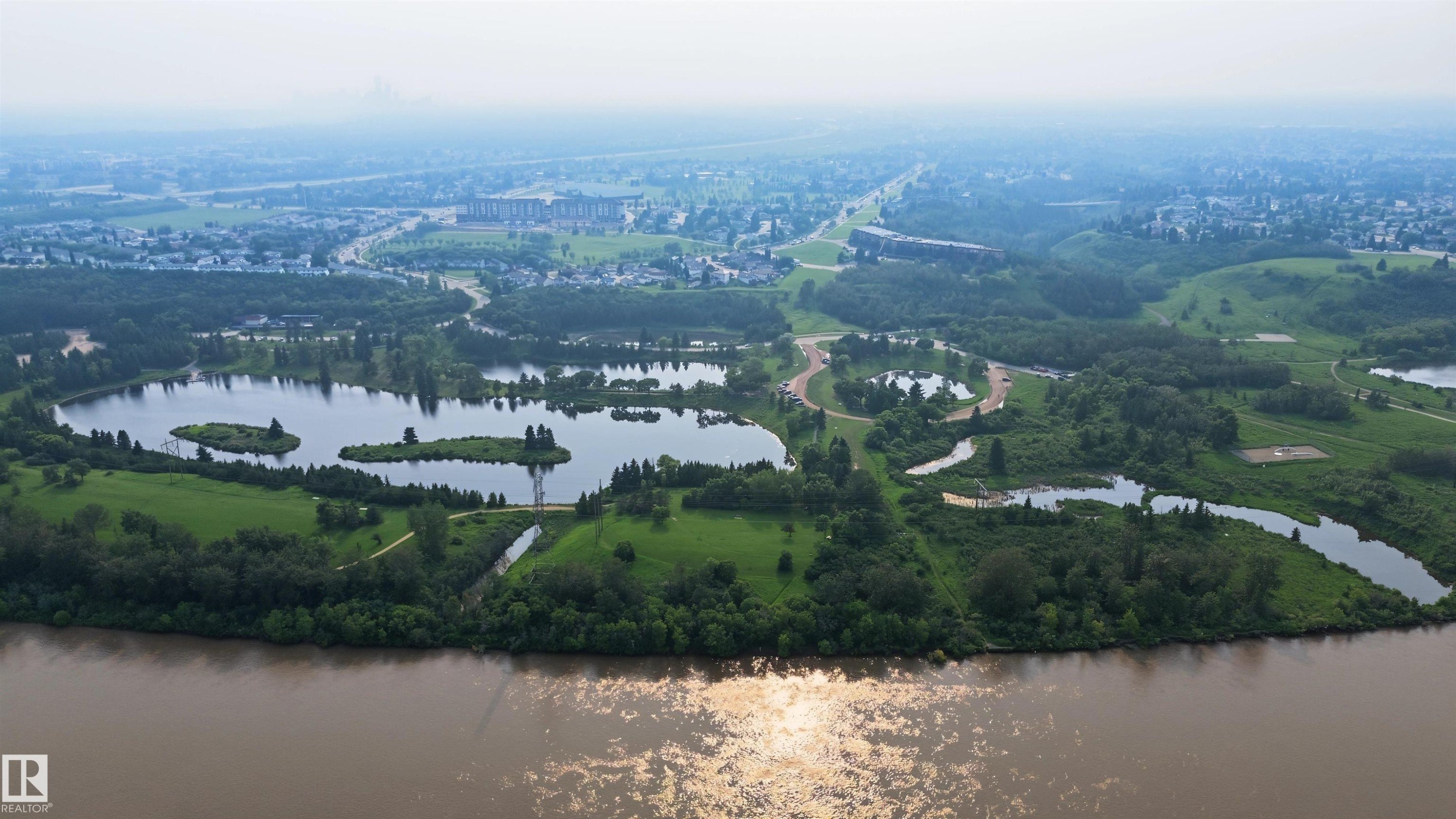 Expansive natural landscape featuring a broad riverfront, multiple interconnected ponds, and abundant mature trees - 15 450 Hyndman Crescent, Edmonton, AB