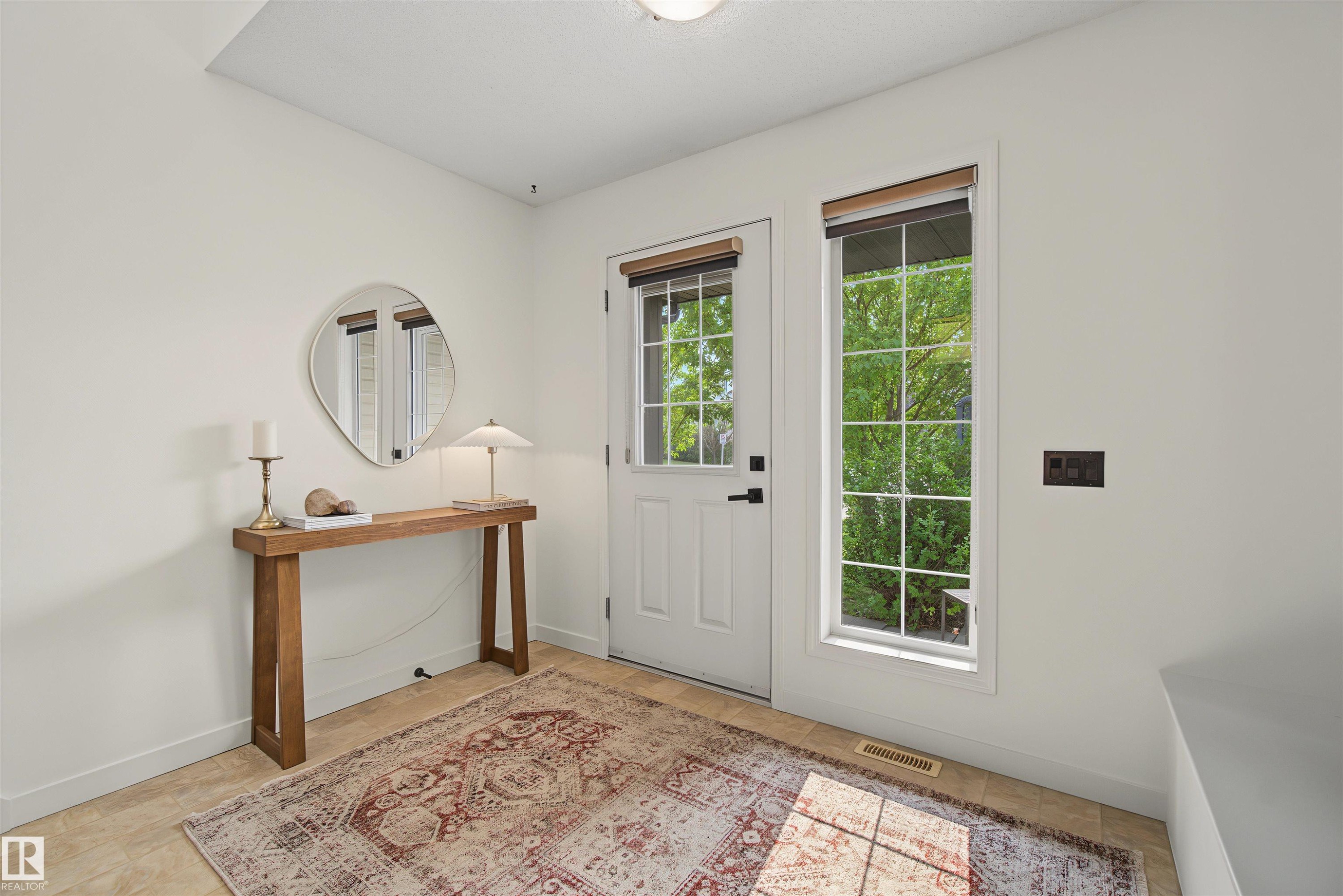 Entryway featuring a white paneled door with glass insert, grid-paned window, tile flooring, and light-toned walls - 15 450 Hyndman Crescent, Edmonton, AB