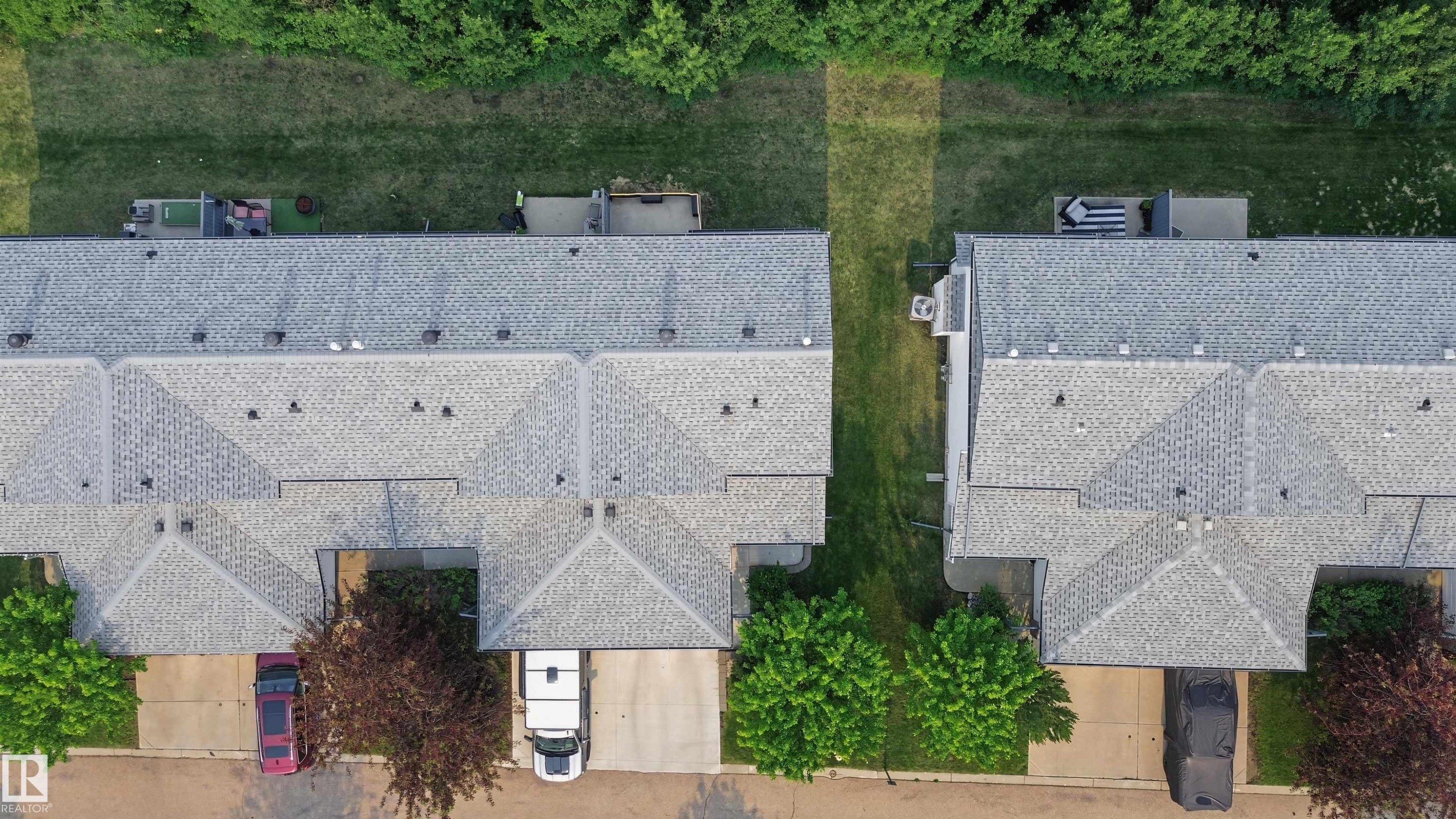 Aerial perspective of multiple properties featuring light gray shingle roofs, individual driveways, and private rear patios - 15 450 Hyndman Crescent, Edmonton, AB