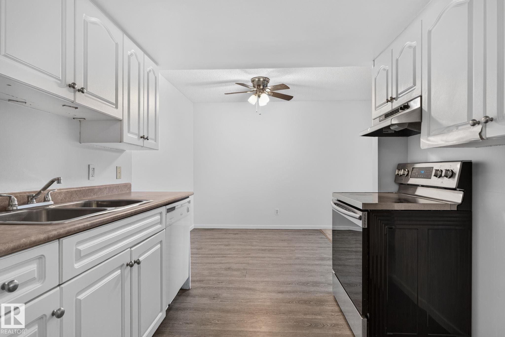 Kitchen featuring white cabinetry, a double basin sink, and a white dishwasher - 401 2908 116A Avenue, Edmonton, AB