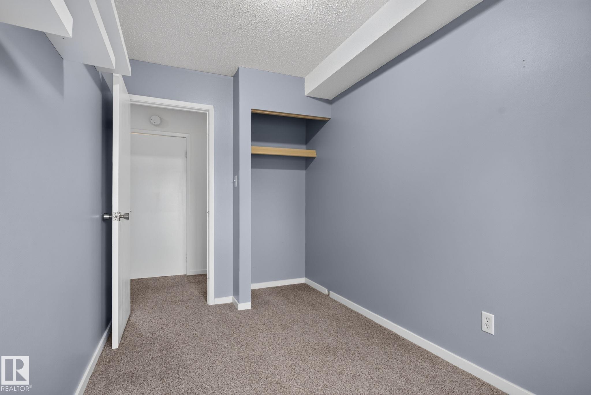 Interior room featuring light grey walls, textured ceiling, light brown carpet, and white trim - 401 2908 116A Avenue, Edmonton, AB