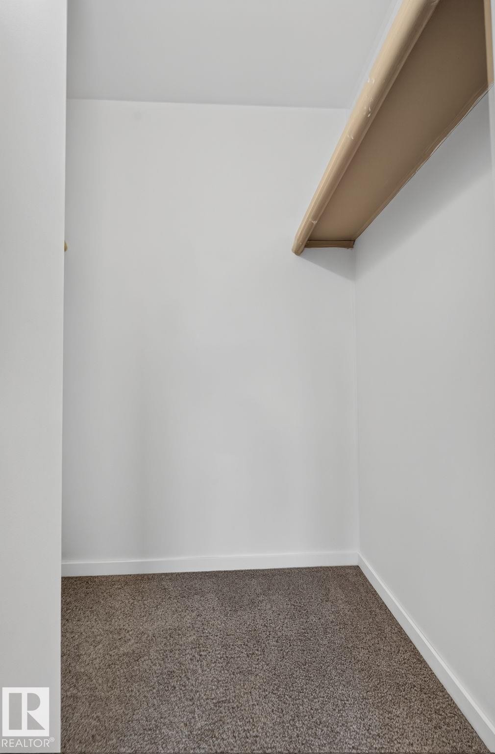 Walk-in closet with overhead shelving, neutral carpeting, and white baseboards - 401 2908 116A Avenue, Edmonton, AB