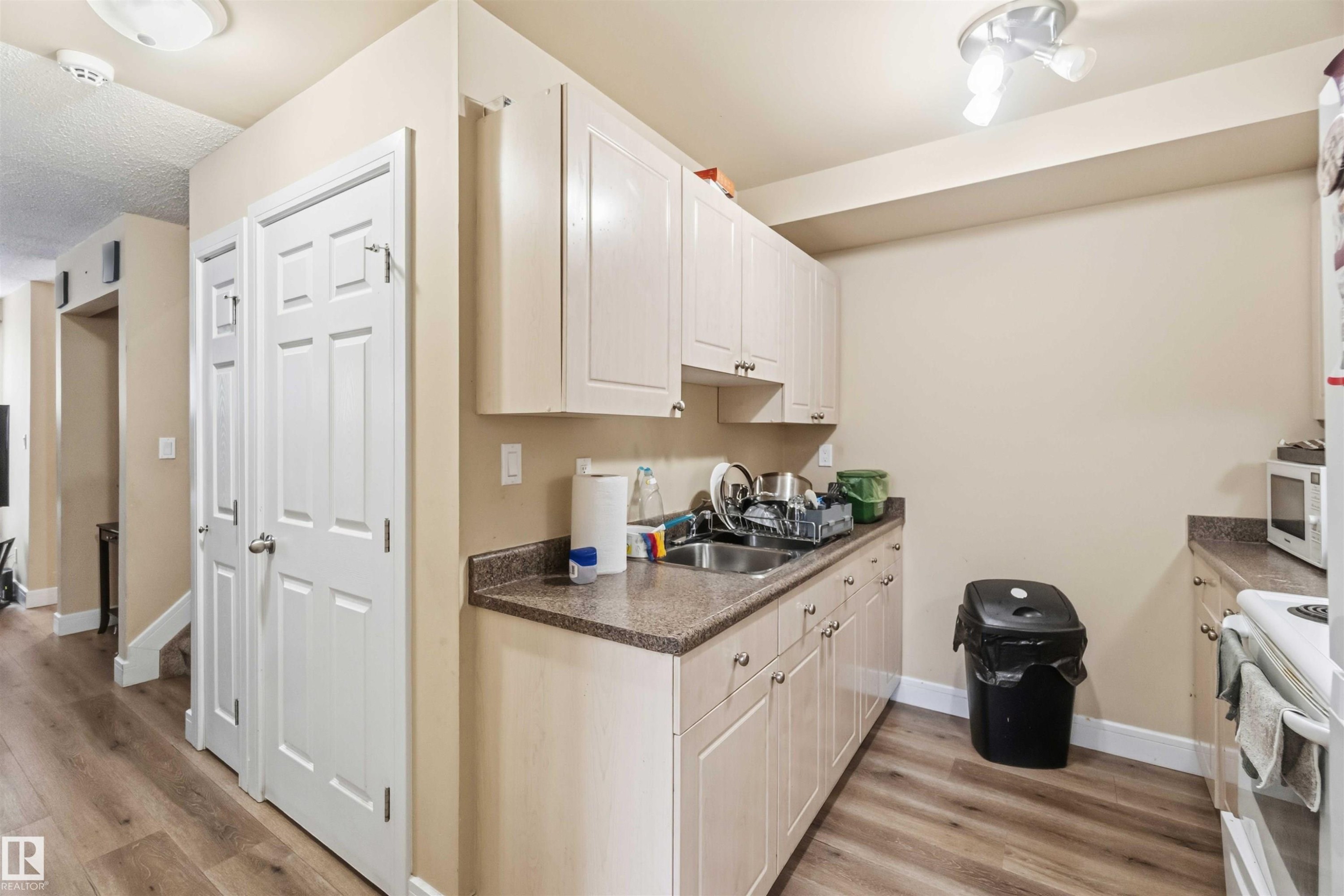 Kitchen area featuring cream cabinetry, a stainless steel double-basin sink, and a speckled countertop - 17118 108 Street, Edmonton, AB