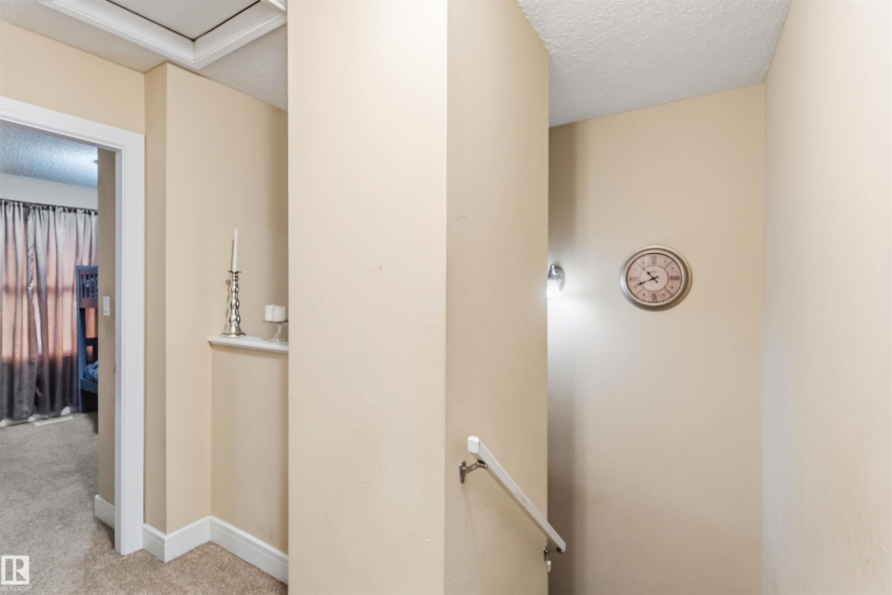 Hallway featuring neutral wall paint, white trim, and a built-in wall niche - 17118 108 Street, Edmonton, AB