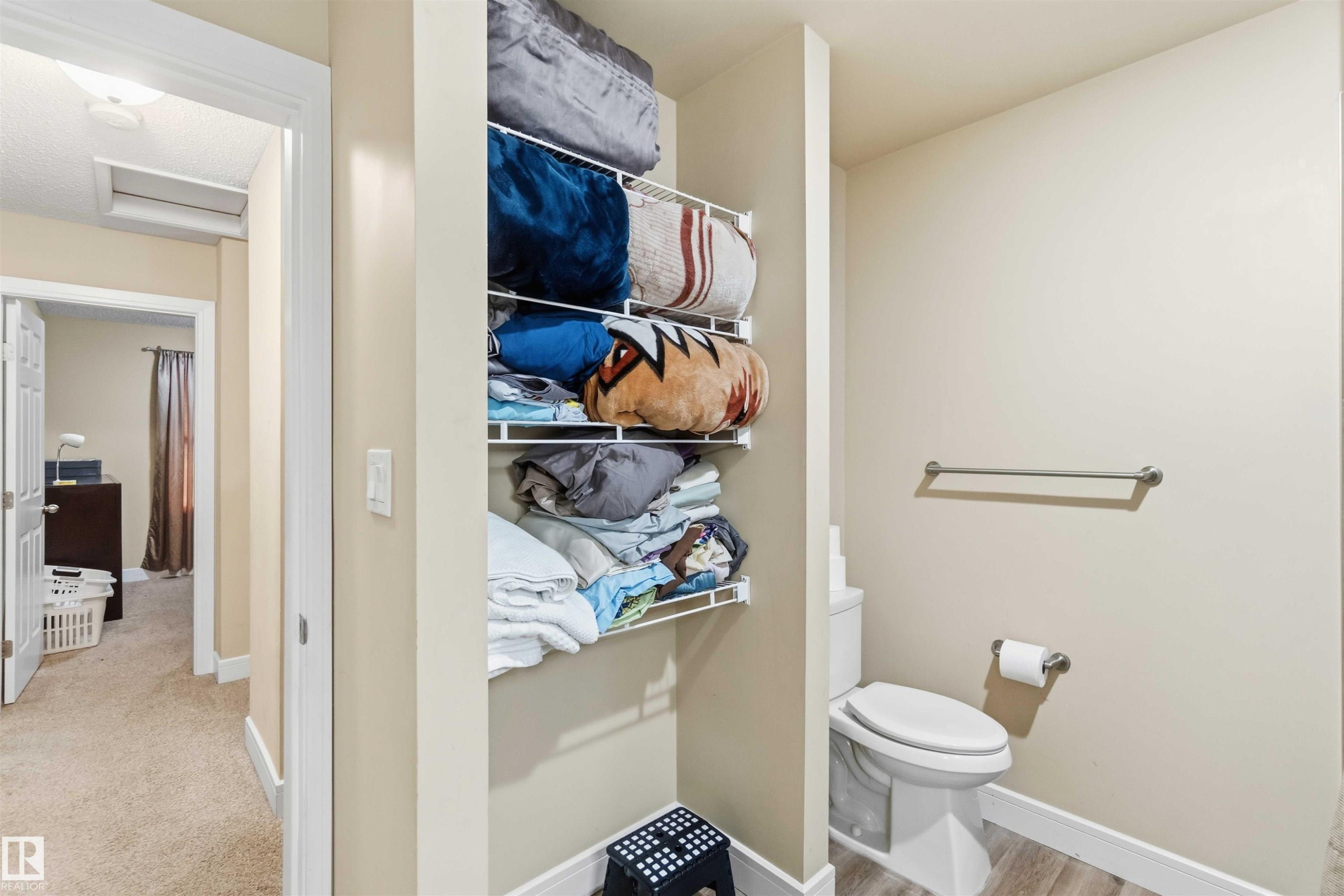 Built-in shelving for organized storage, alongside a commode with a toilet paper holder and towel bar - 17118 108 Street, Edmonton, AB
