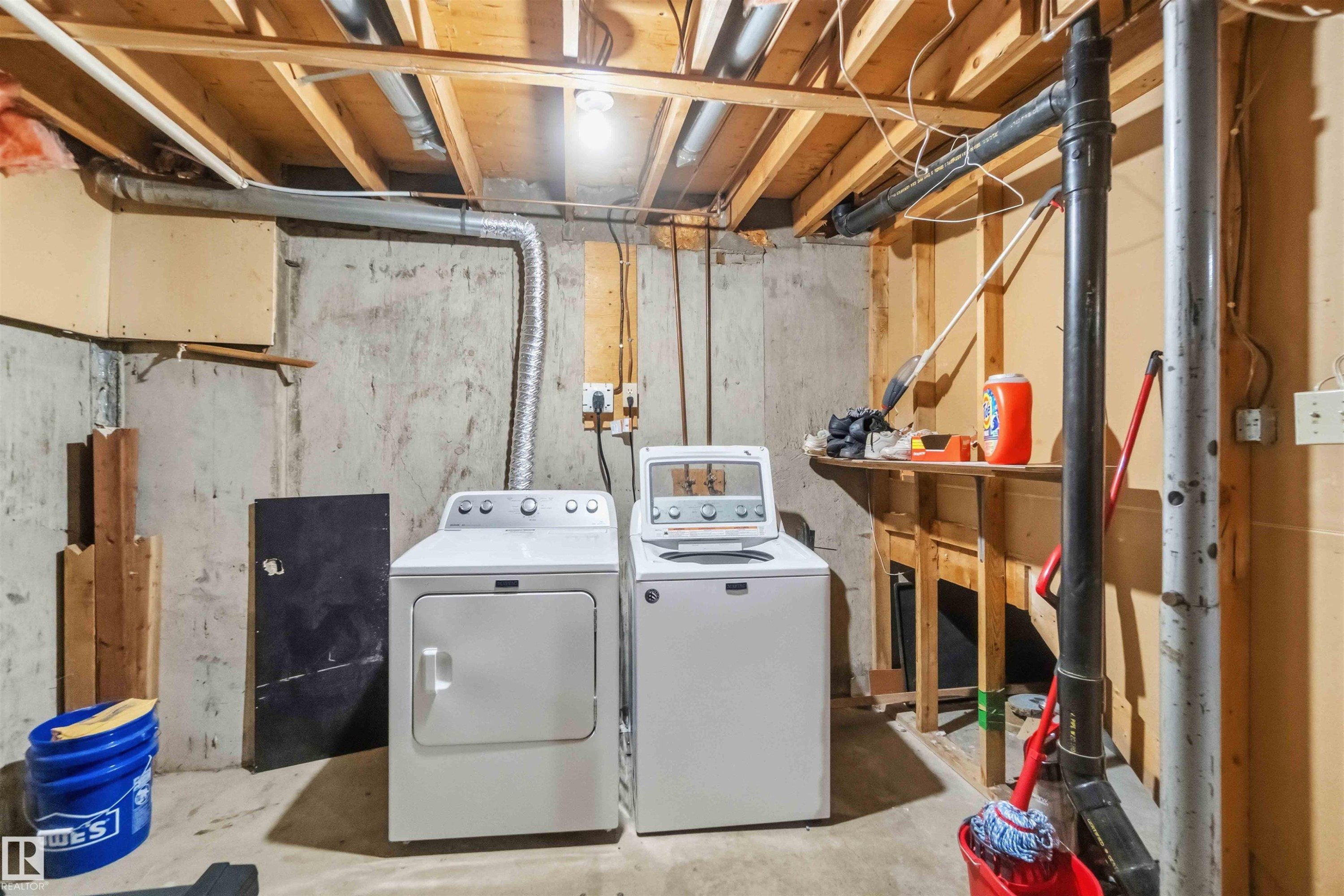 Basement laundry area featuring concrete walls, exposed ceiling joists, and a utility sink - 17118 108 Street, Edmonton, AB