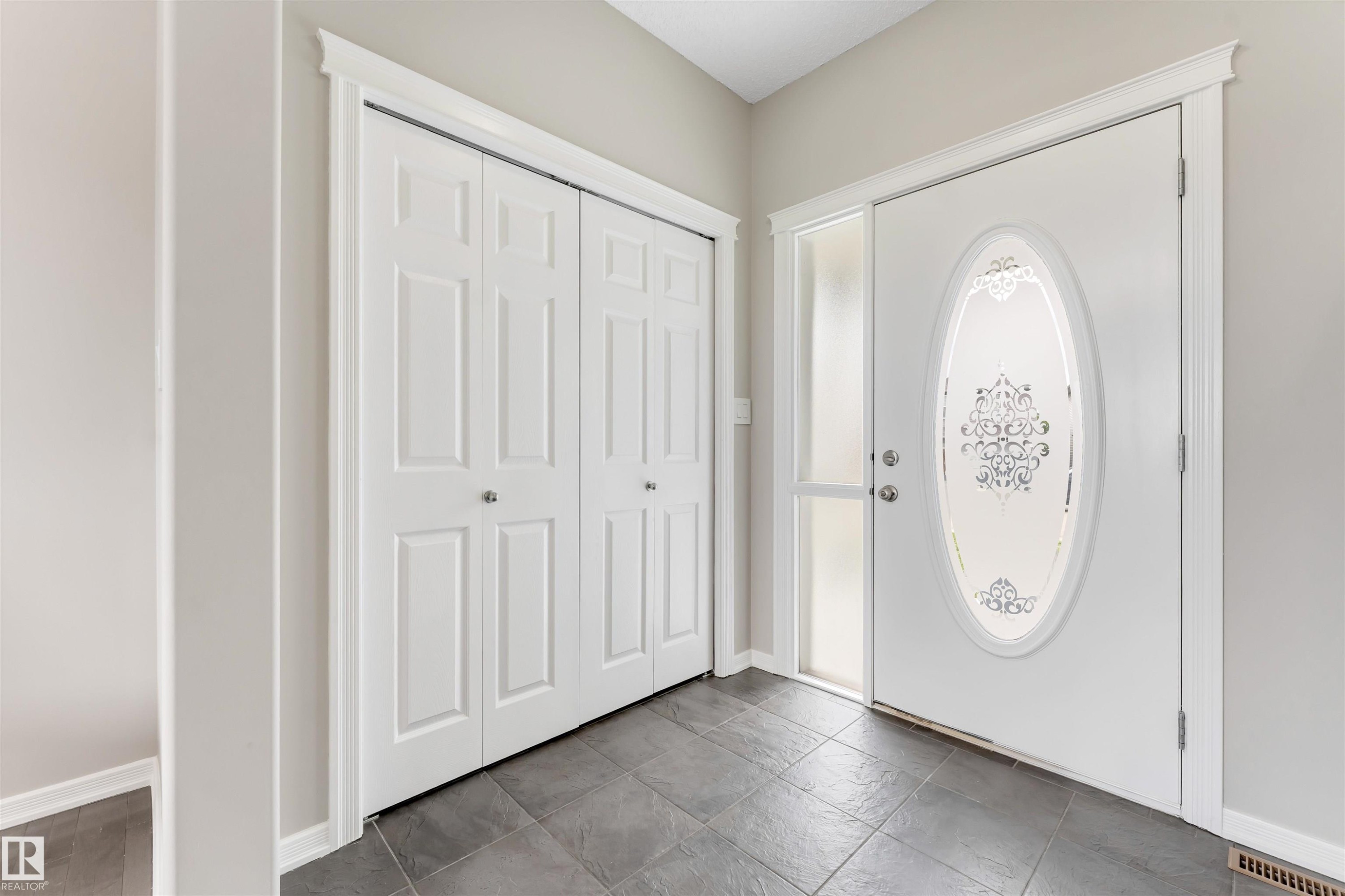 Entryway featuring a white paneled door with an oval frosted glass insert, a full-length frosted sidelight, and crown molding trim - 3449 28 Street, Edmonton, AB
