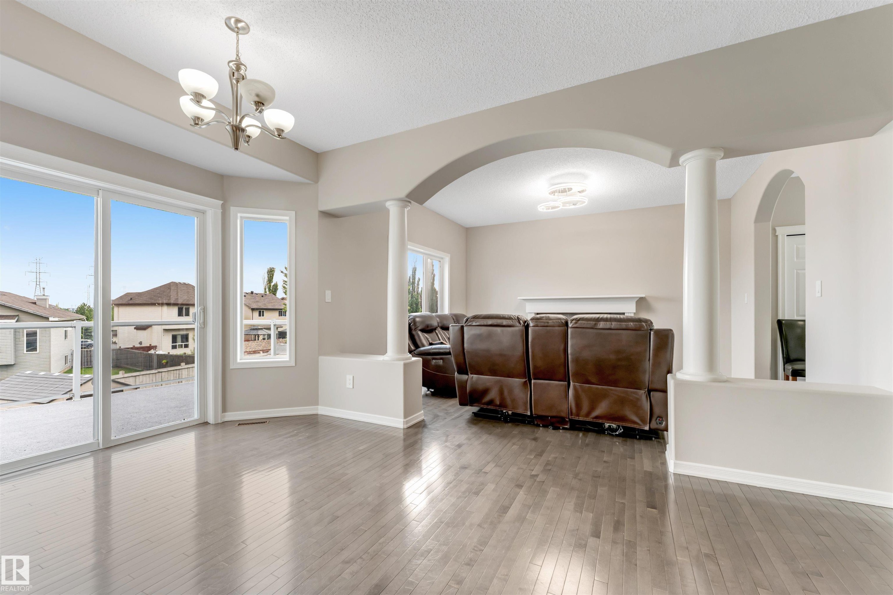 Open-concept interior featuring wood-finish flooring, neutral wall tones, and a brushed nickel chandelier - 3449 28 Street, Edmonton, AB
