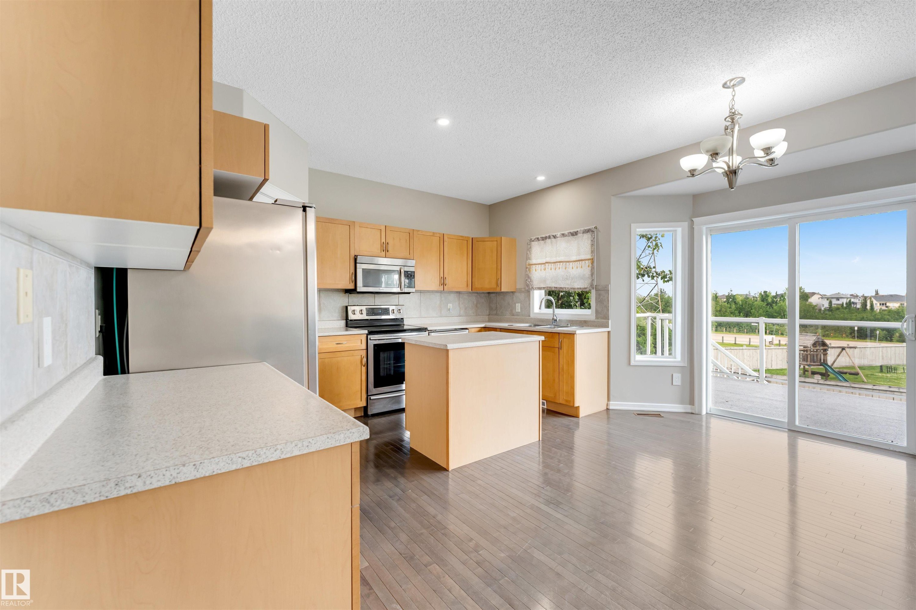 Kitchen featuring wood-finish flooring, light-toned cabinetry, and stainless steel appliances - 3449 28 Street, Edmonton, AB