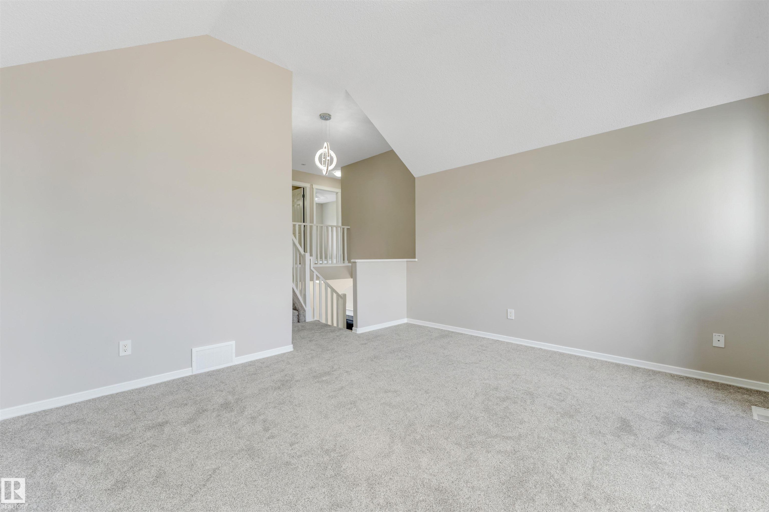 Spacious room featuring vaulted ceilings, light gray wall paint, and light gray carpeted flooring - 3449 28 Street, Edmonton, AB