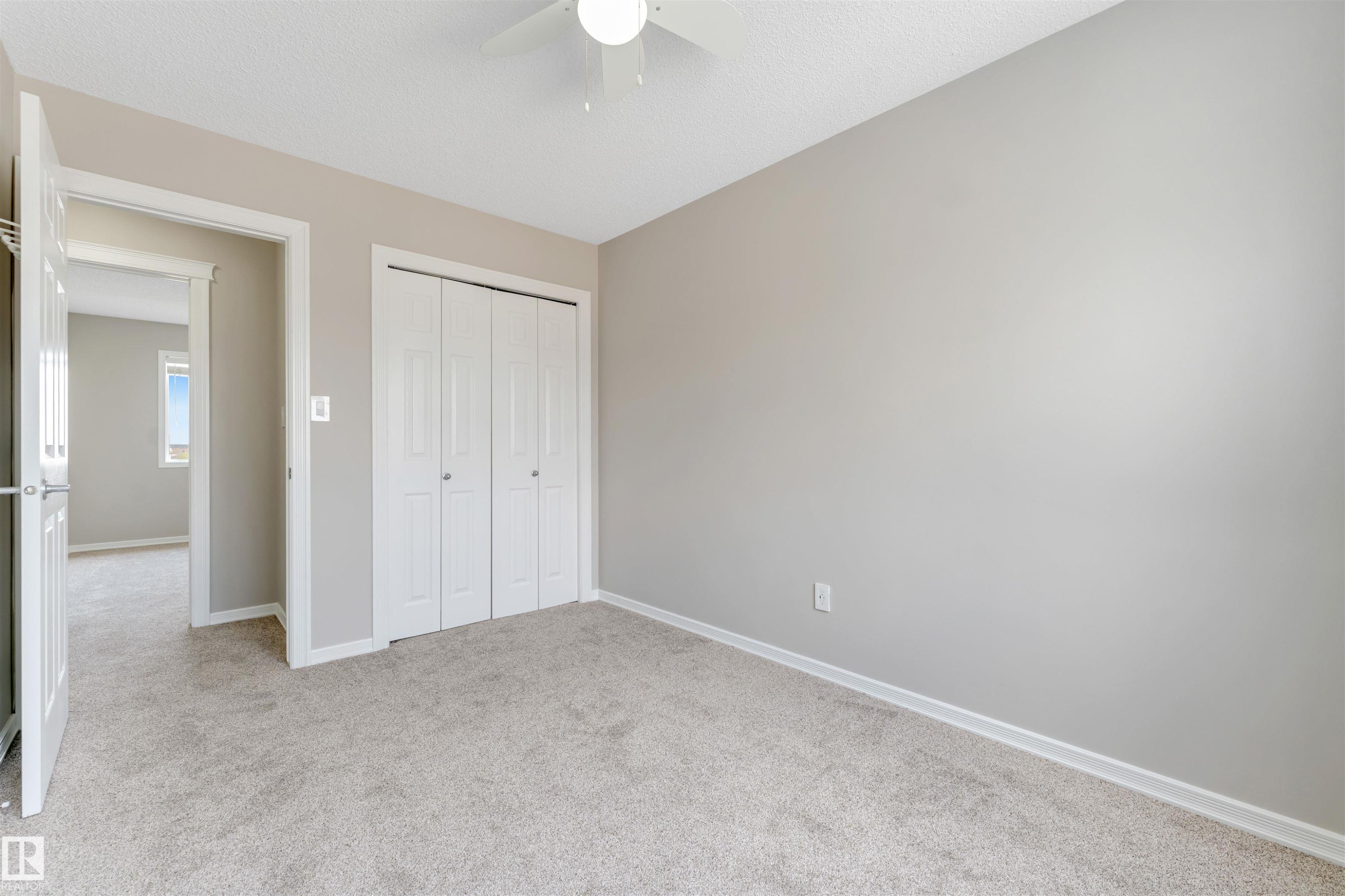 Light gray wall paint, plush carpeting, white bi-fold closet doors, white baseboards, and a ceiling fan with light fixture - 3449 28 Street, Edmonton, AB