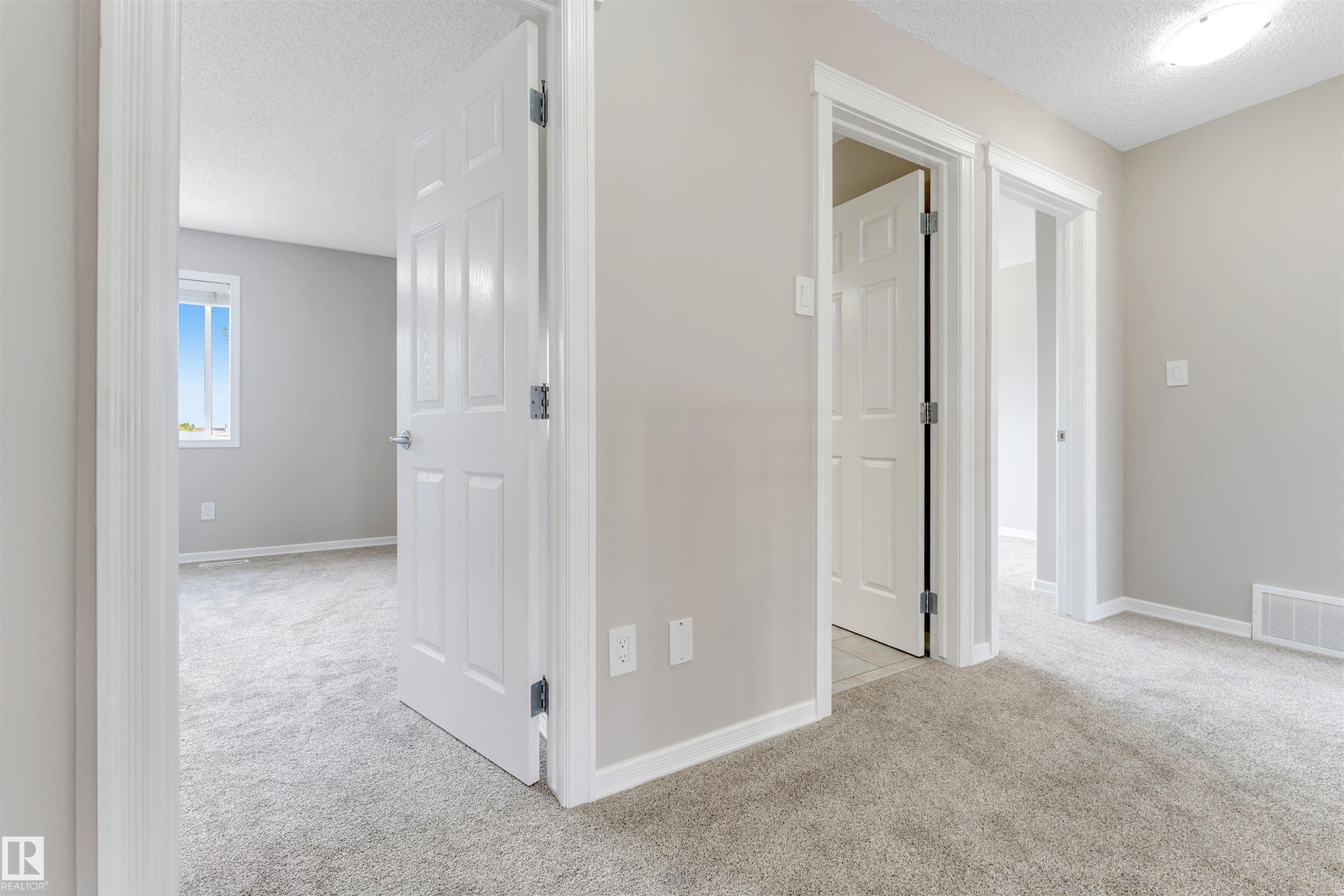 Interior hallway featuring light gray walls, white trim, and plush carpet flooring - 3449 28 Street, Edmonton, AB
