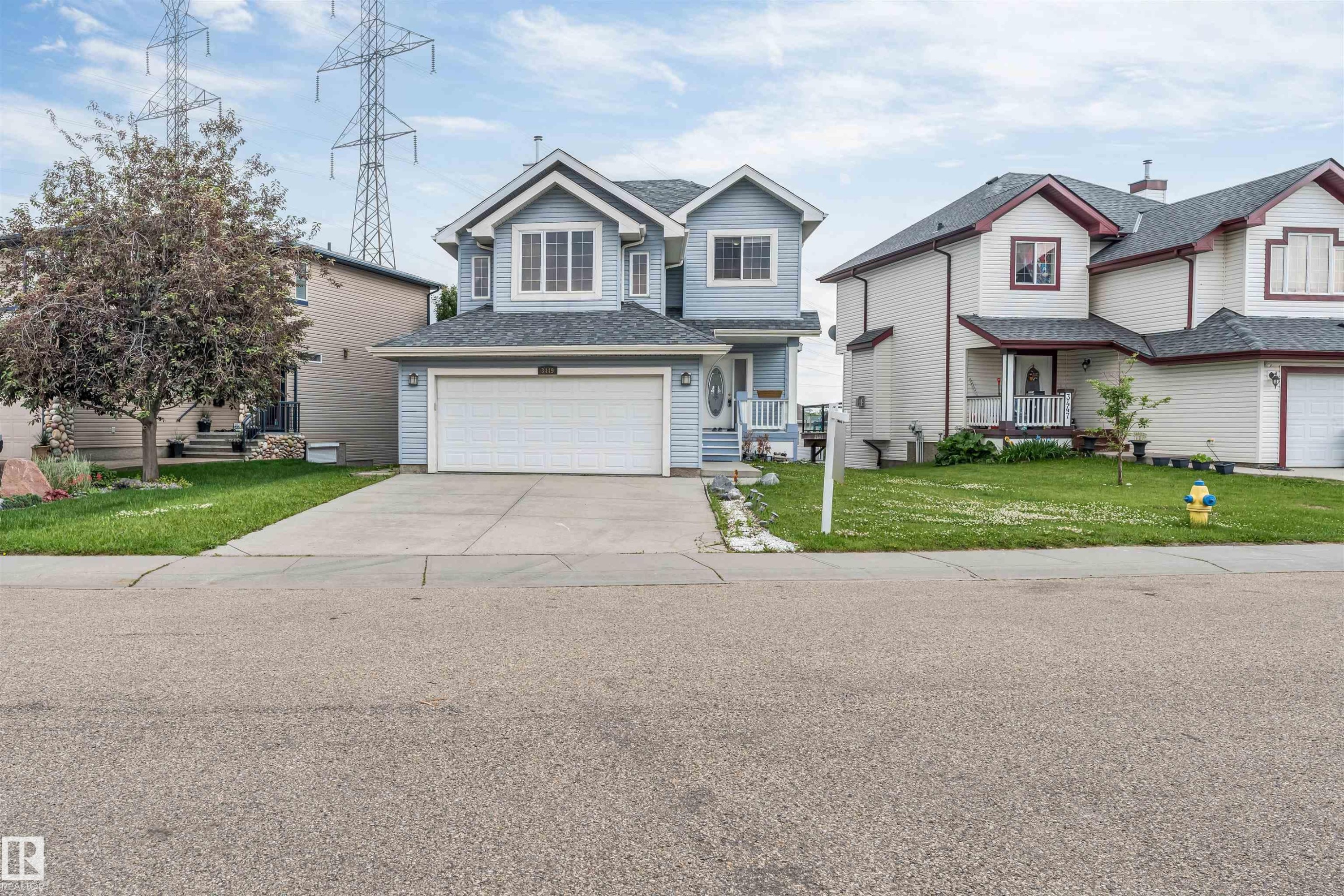 Two-story residence featuring light blue siding with white trim, a dark shingled roof, and an attached two-car garage - 3449 28 Street, Edmonton, AB