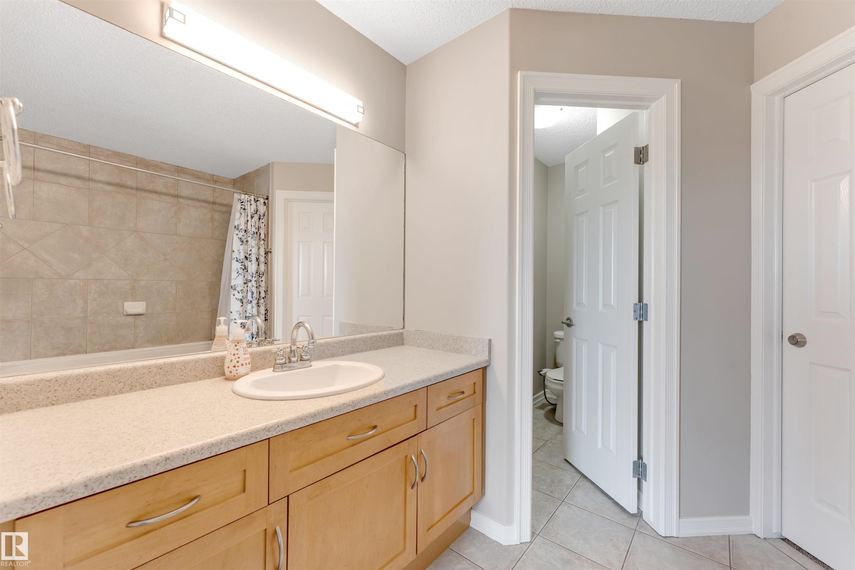 Bathroom vanity featuring light wood cabinetry, a light-toned countertop, and an integrated sink - 3449 28 Street, Edmonton, AB