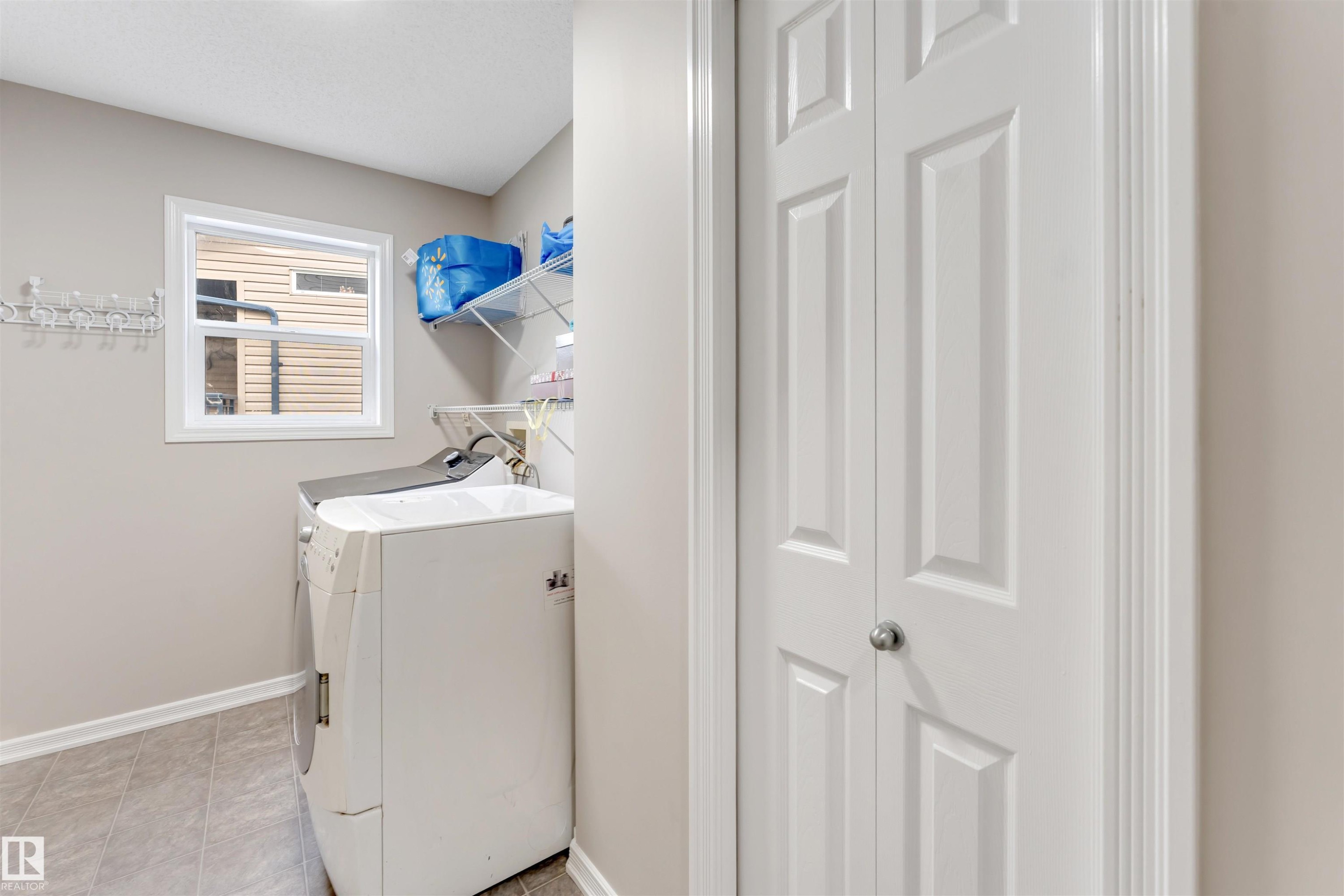 Dedicated laundry area featuring a window, built-in shelving, and a wall-mounted drying rack - 3449 28 Street, Edmonton, AB