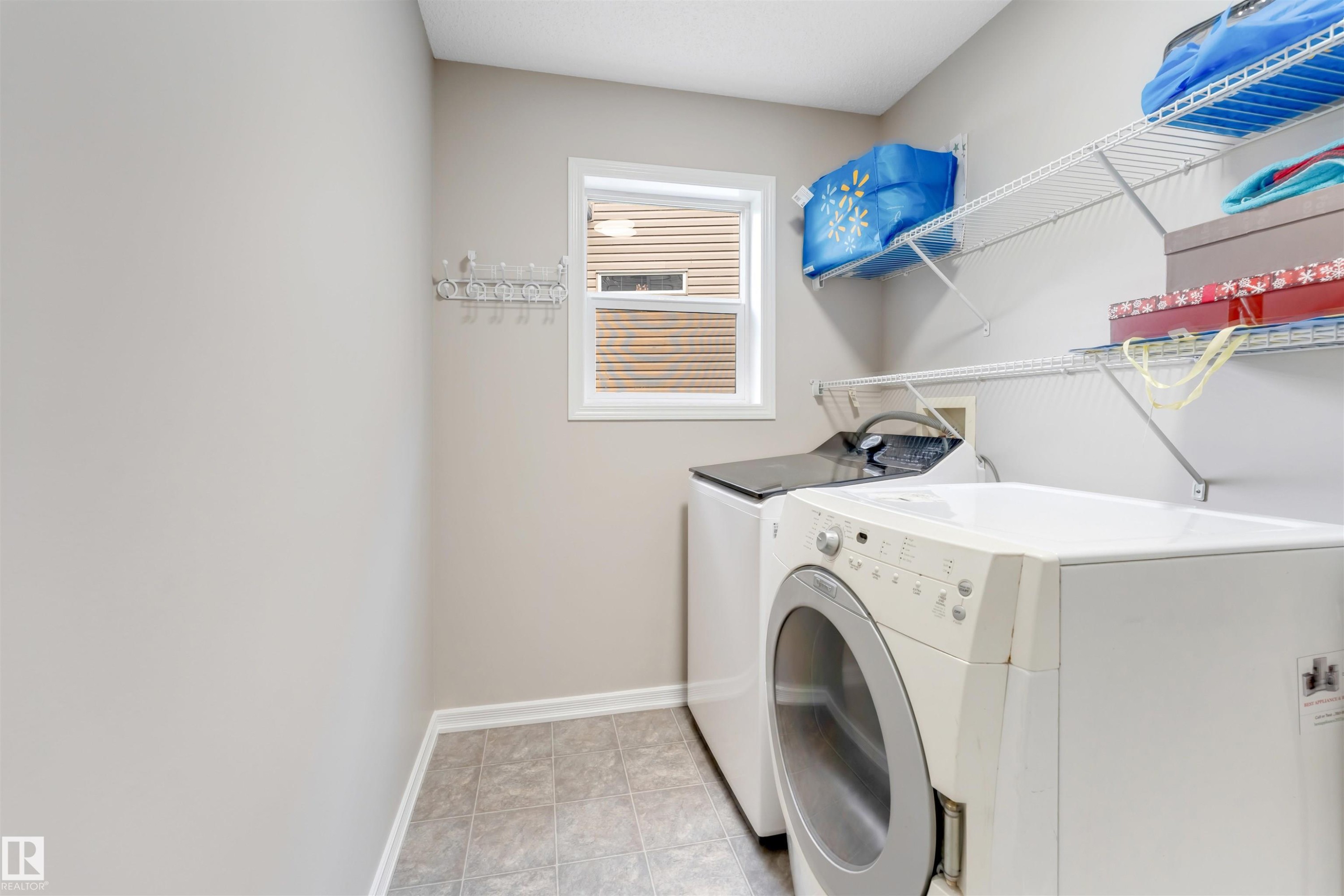 Dedicated laundry area featuring a window, tile flooring, and wall-mounted wire shelving - 3449 28 Street, Edmonton, AB