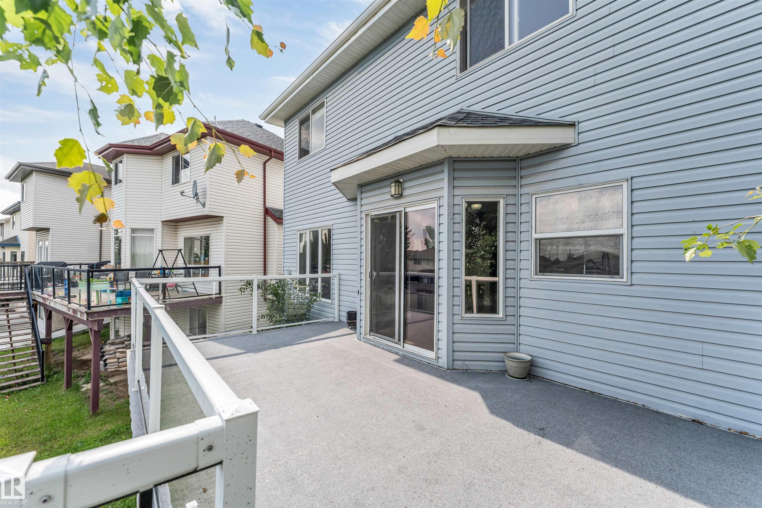 Spacious exterior deck featuring a glass railing system and direct access to the interior via sliding glass doors - 3449 28 Street, Edmonton, AB
