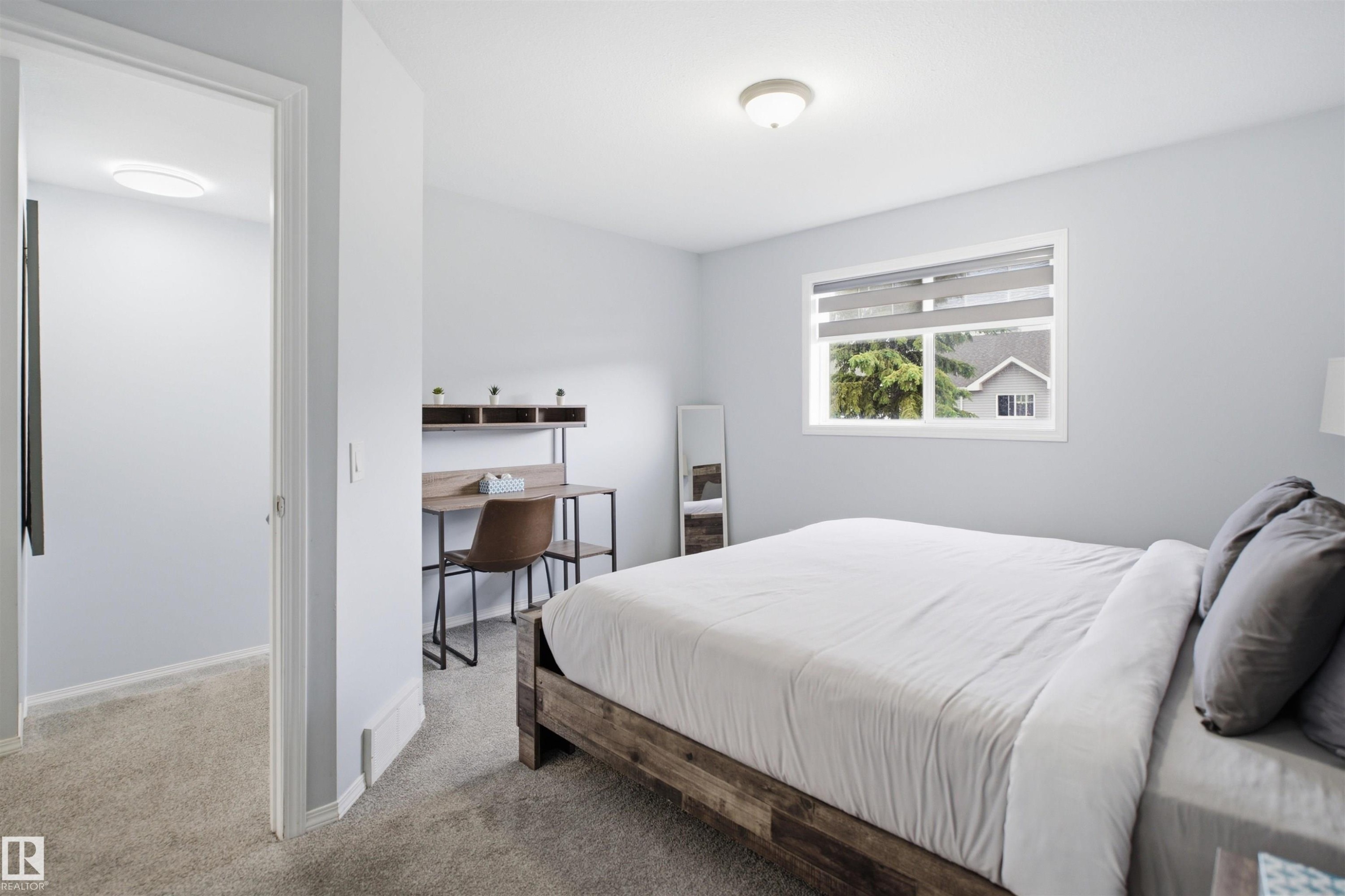 Carpeted room featuring a double-paned window with roller shades, a flush-mount ceiling light, and light-colored walls - 92 230 Edwards Drive, Edmonton, AB