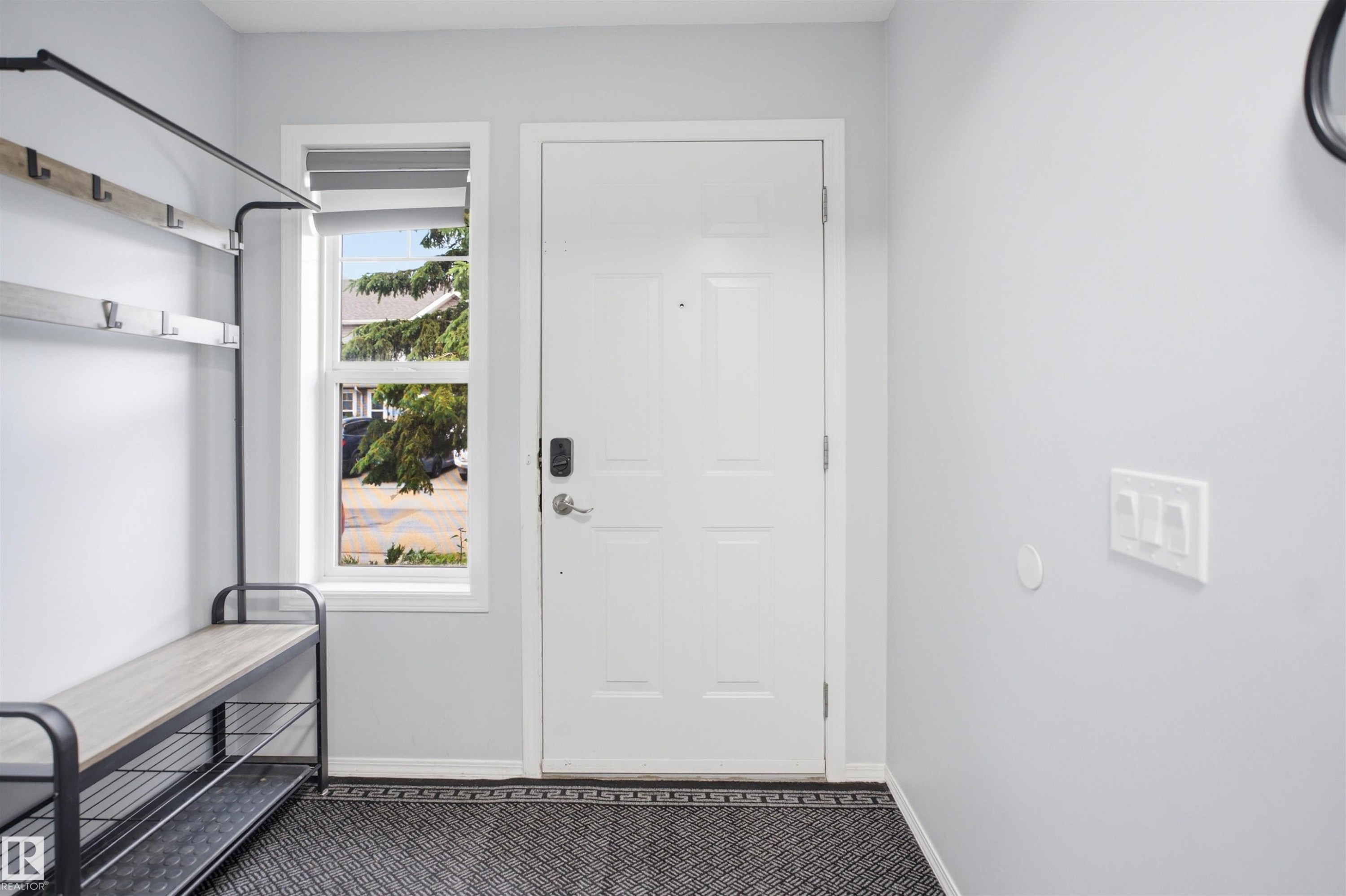 Entryway featuring a white paneled door with smart lock hardware, a large side window, and light gray wall finishes - 92 230 Edwards Drive, Edmonton, AB