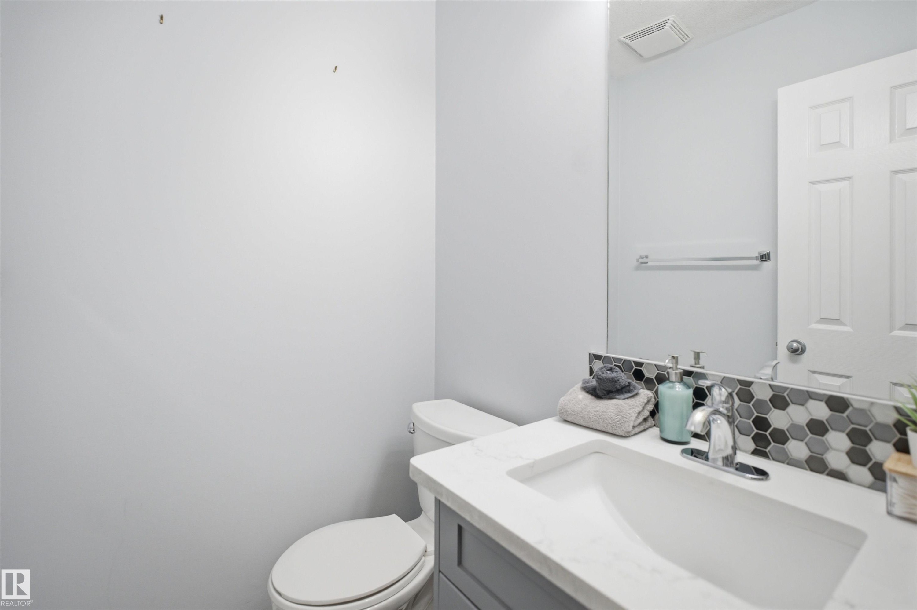 Bathroom vanity featuring a rectangular undermount sink, a countertop with a marble-effect finish, and a hexagonal tile backsplash - 92 230 Edwards Drive, Edmonton, AB