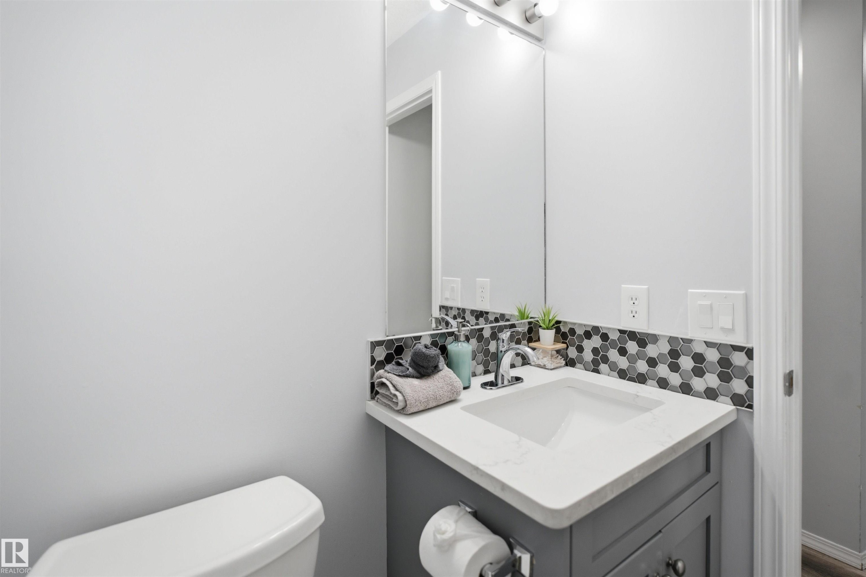 Modern vanity featuring a white countertop with integrated sink, chrome faucet, and gray cabinetry - 92 230 Edwards Drive, Edmonton, AB
