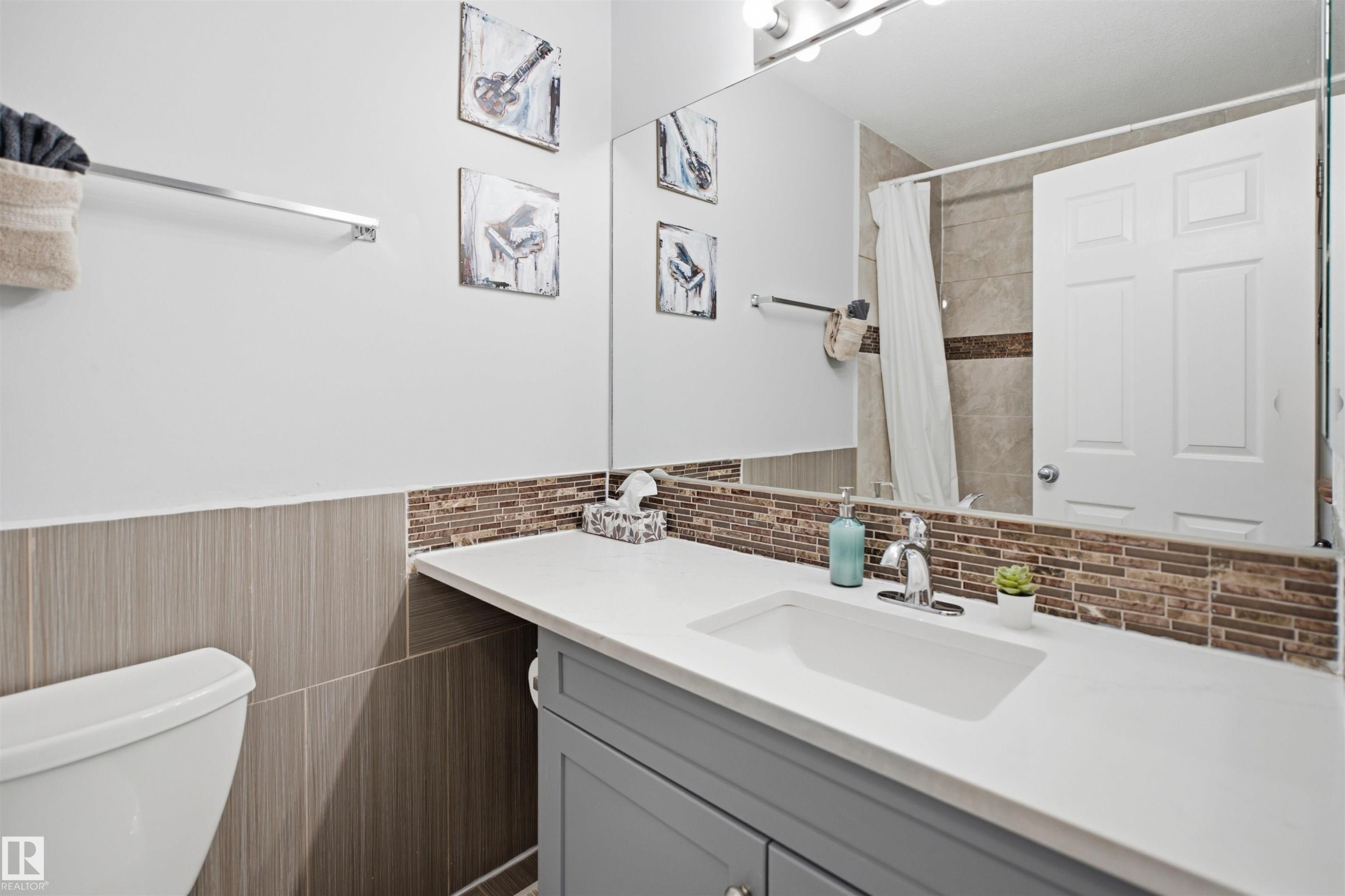 Bathroom vanity featuring an integrated rectangular sink, chrome faucet, and white countertop - 92 230 Edwards Drive, Edmonton, AB