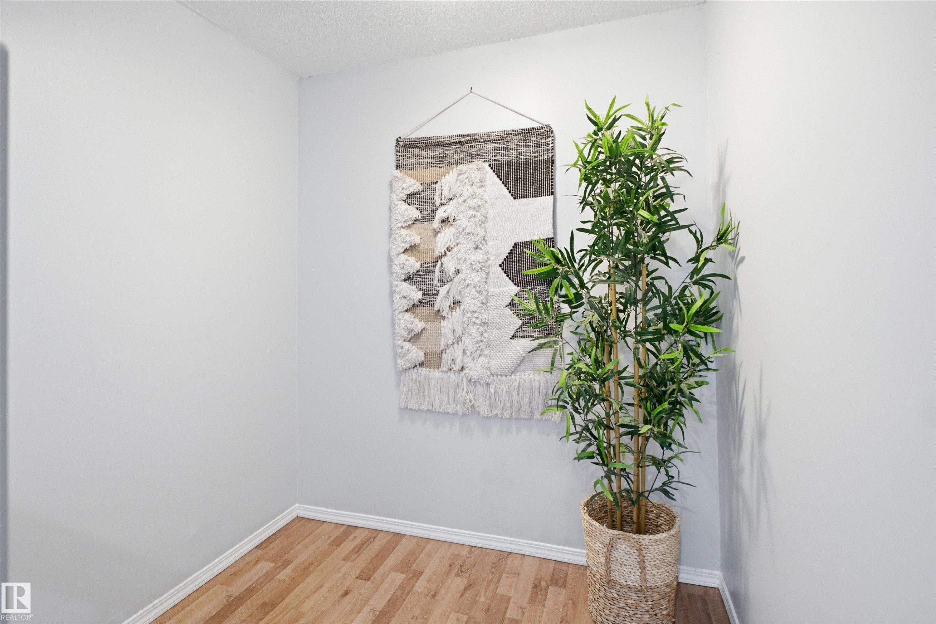 Light wood-finish flooring with white baseboards and light-toned walls create a neutral palette - 92 230 Edwards Drive, Edmonton, AB