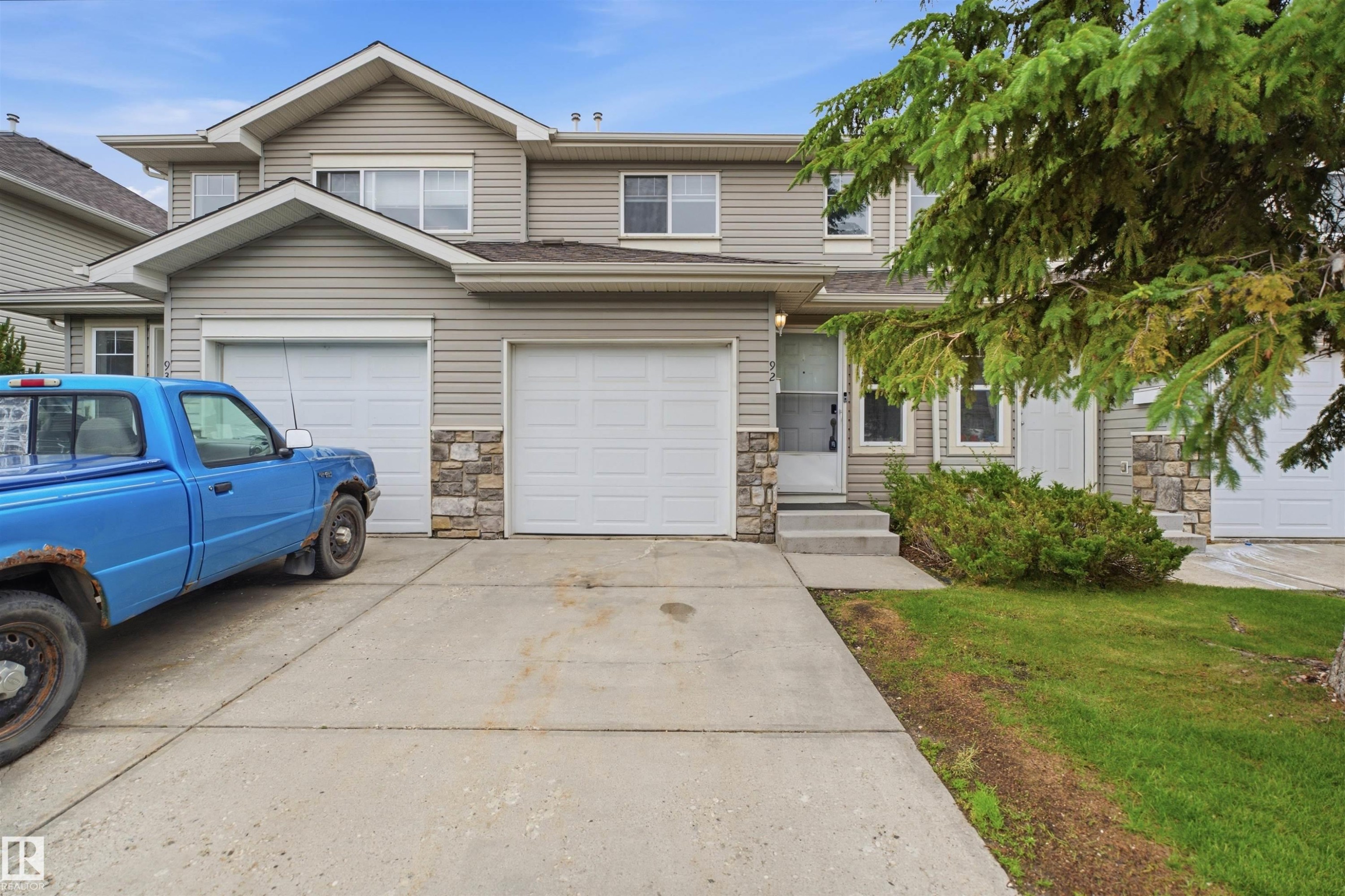 Two-story residence featuring light-colored siding and stone accents - 92 230 Edwards Drive, Edmonton, AB