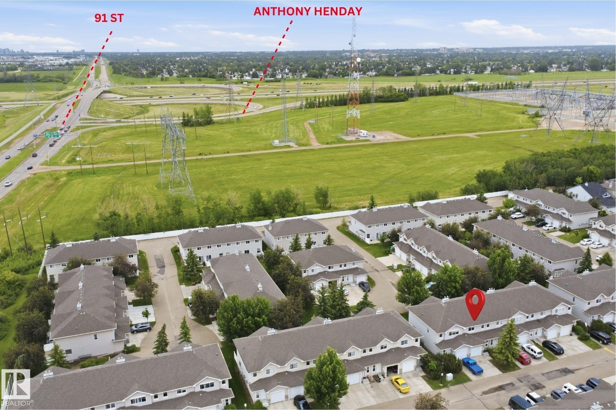 Townhouse property featuring a light-colored exterior, an attached garage, and a peaked roof - 92 230 Edwards Drive, Edmonton, AB