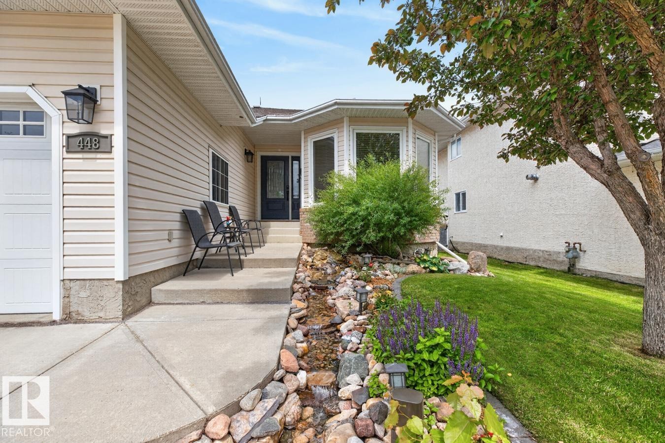Front exterior featuring beige horizontal siding and a dark blue entry door - 448 Ormsby Road Nw, Edmonton, AB - Outdoor