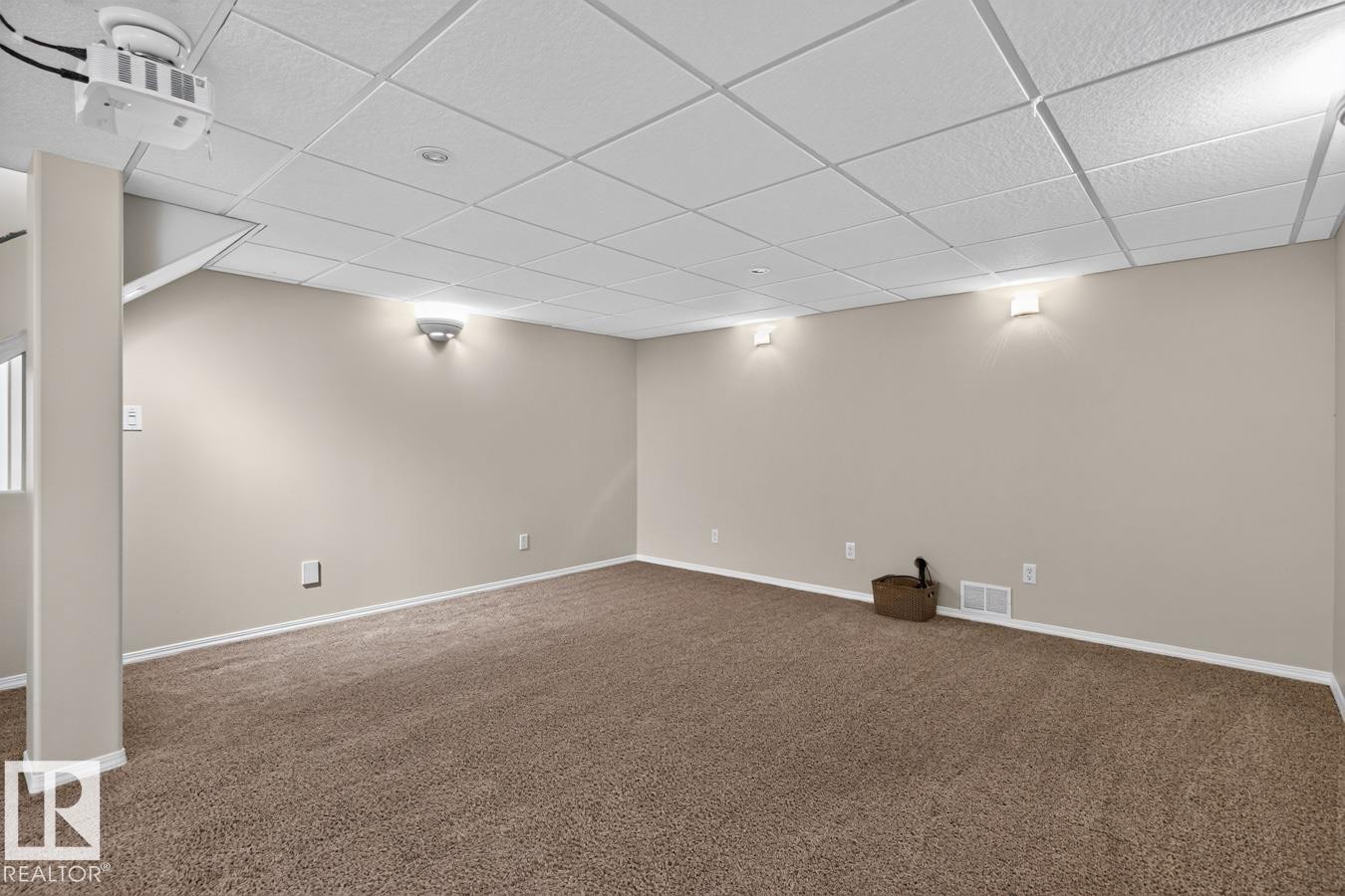 Spacious room featuring neutral carpeting, light-toned walls, and a drop ceiling with recessed and wall-mounted lighting - 448 Ormsby Road Nw, Edmonton, AB - Indoor
