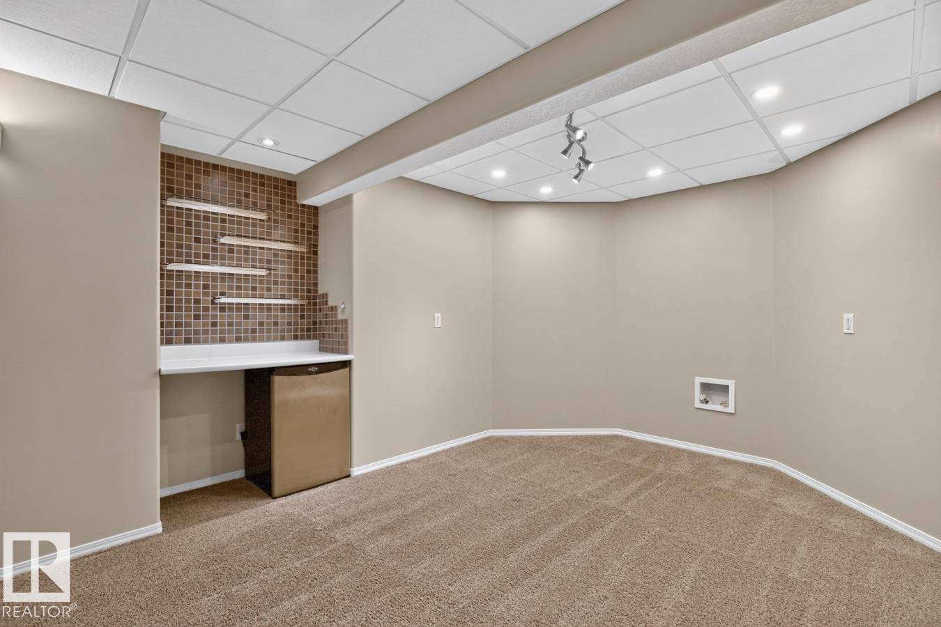 Finished basement featuring a built-in wet bar with a tiled backsplash, floating shelves, and a solid surface countertop - 448 Ormsby Road Nw, Edmonton, AB - Indoor