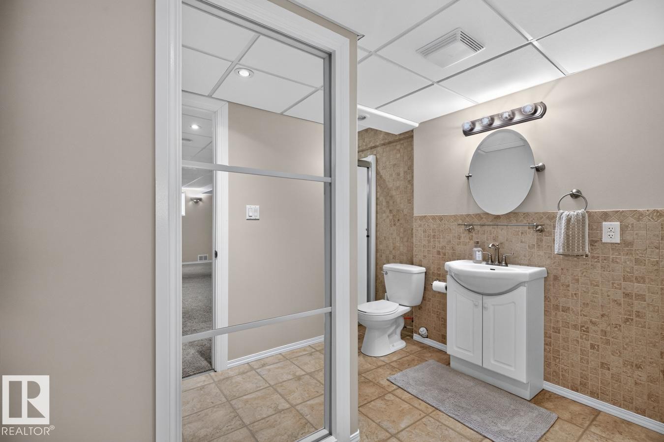Bathroom featuring a contemporary vanity with an integrated sink, ceramic tile flooring, and wainscoting - 448 Ormsby Road Nw, Edmonton, AB - Indoor Photo Showing Bathroom