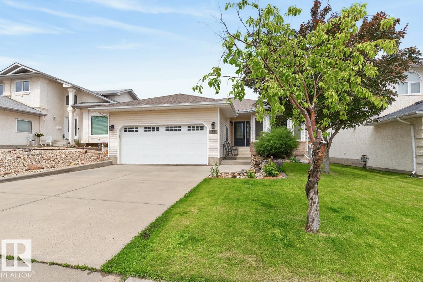 Front exterior featuring a two-car garage with paneling, concrete driveway, and a manicured lawn - 448 Ormsby Road Nw, Edmonton, AB - Outdoor With Facade