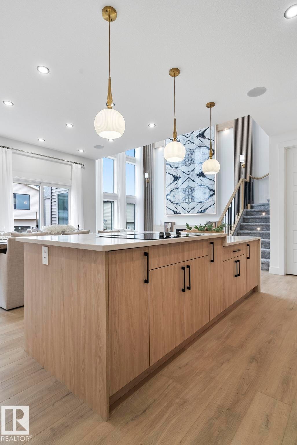 Kitchen island featuring a light wood-finish with matte black hardware, integrated cooktop, and a light-toned countertop - 13152 187 Avenue, Edmonton, AB