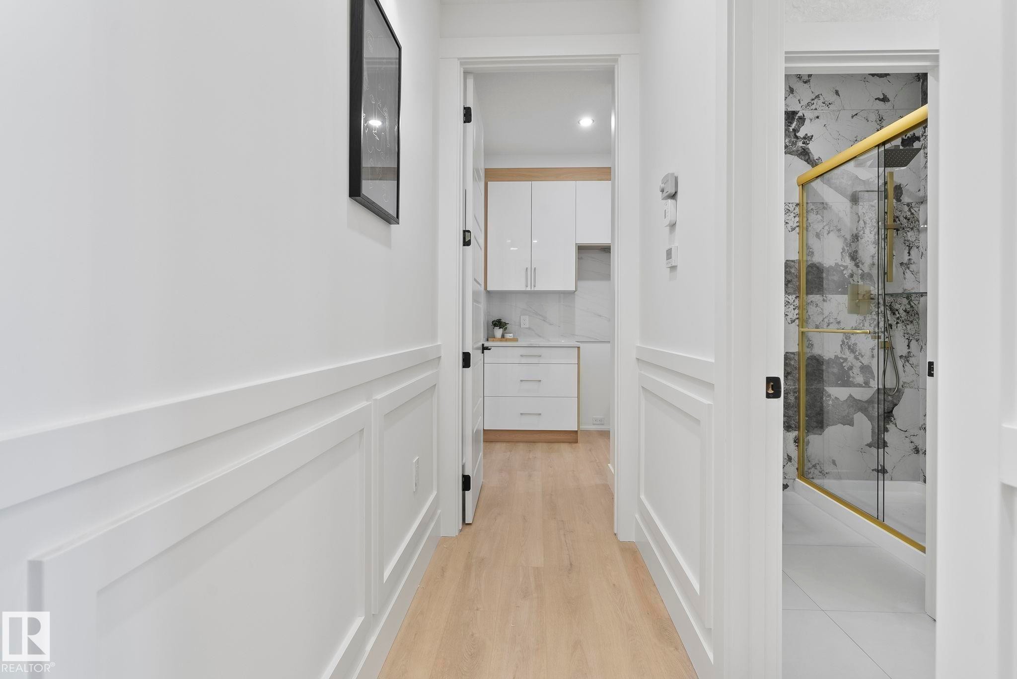 Hallway featuring light wood-finish flooring and white wainscoting - 13152 187 Avenue, Edmonton, AB
