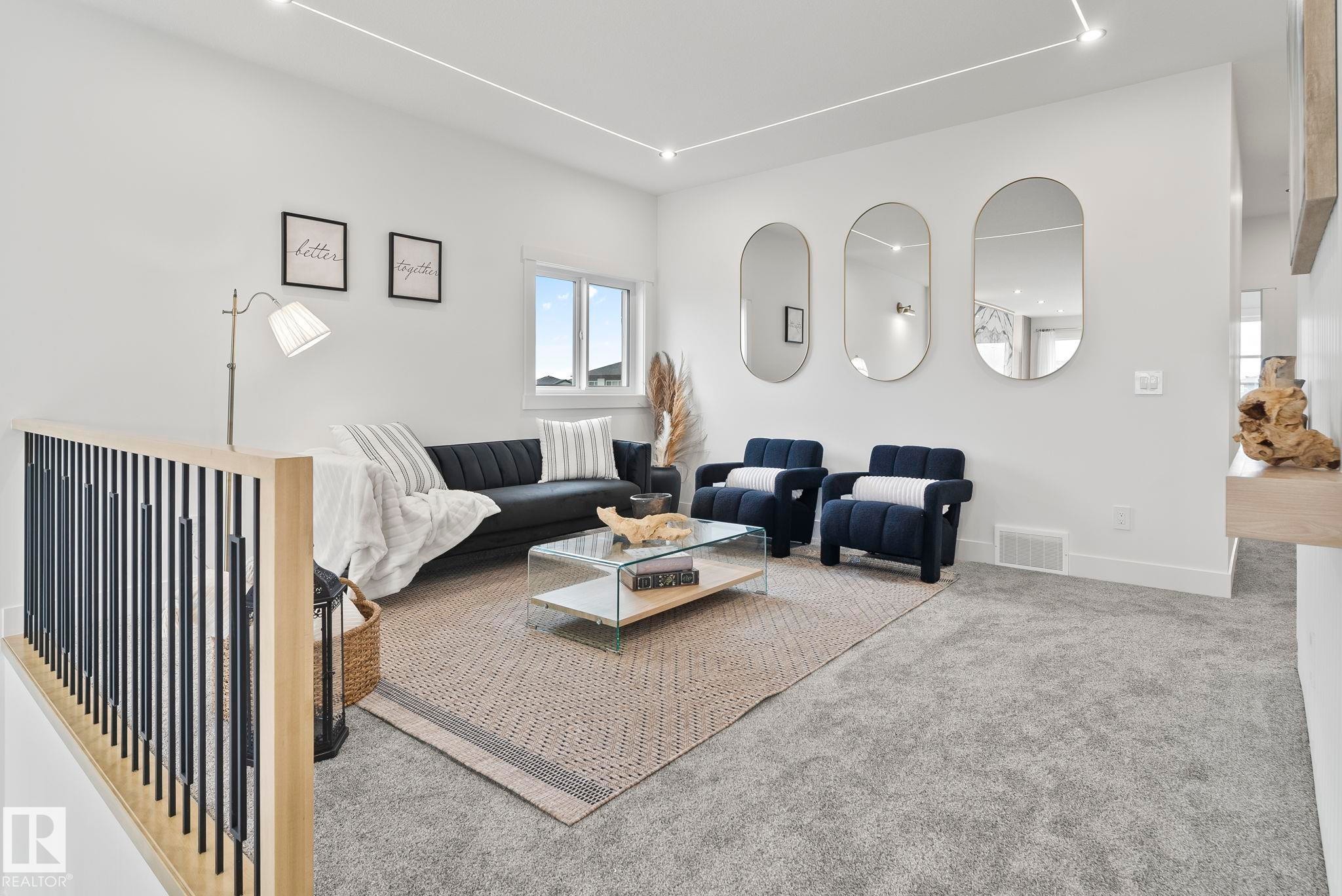 Open living area featuring light-toned carpeting and a contemporary railing with wood and black metal spindles - 13152 187 Avenue, Edmonton, AB