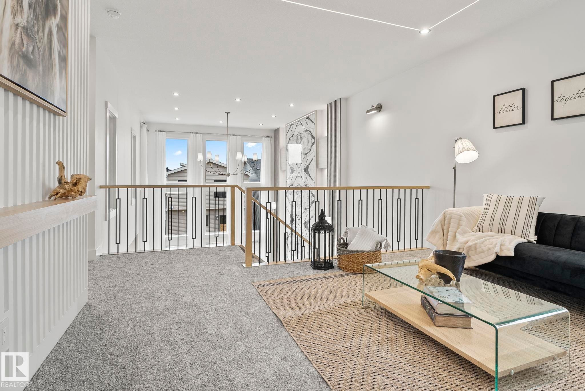 Open loft area featuring light gray carpet flooring and a contemporary railing with wood-finish handrails and black metal spindles - 13152 187 Avenue, Edmonton, AB