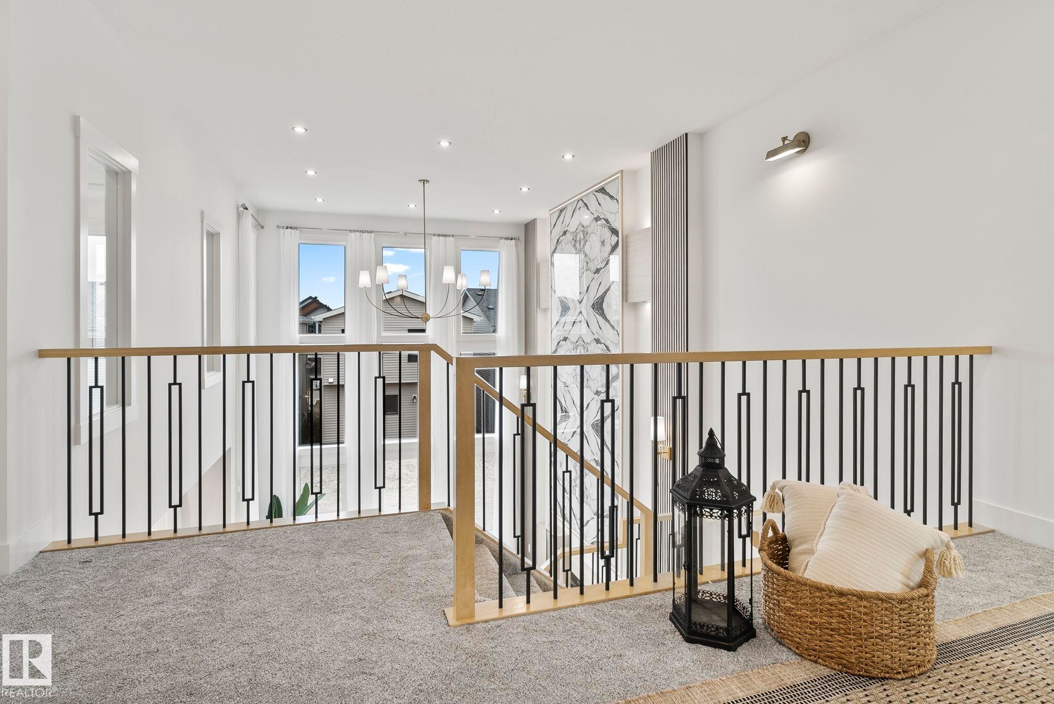 Upper-level landing featuring light gray carpeting, contemporary metal and wood-finish railing, recessed lighting, and wall-mounted sconces - 13152 187 Avenue, Edmonton, AB