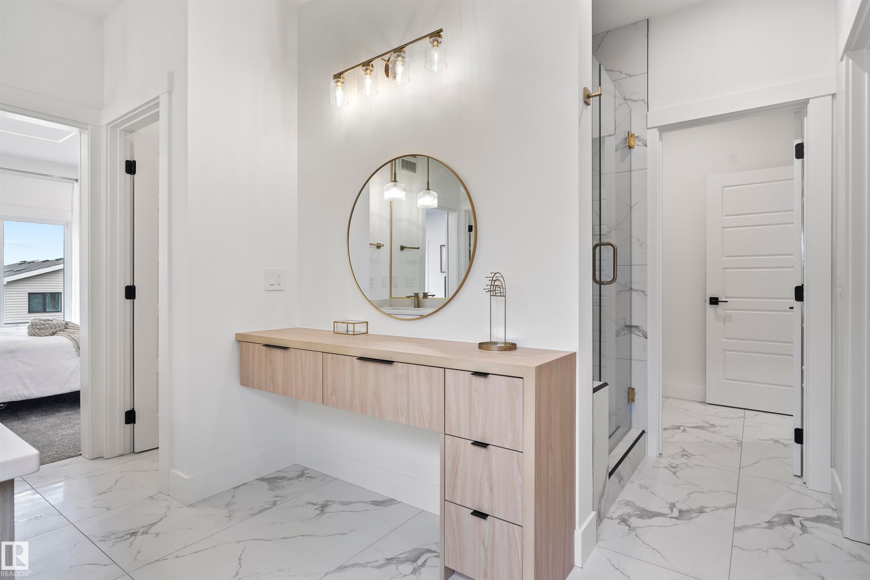 Floating wood-finish vanity with drawer storage, illuminated by a brass-finish light fixture - 13152 187 Avenue, Edmonton, AB