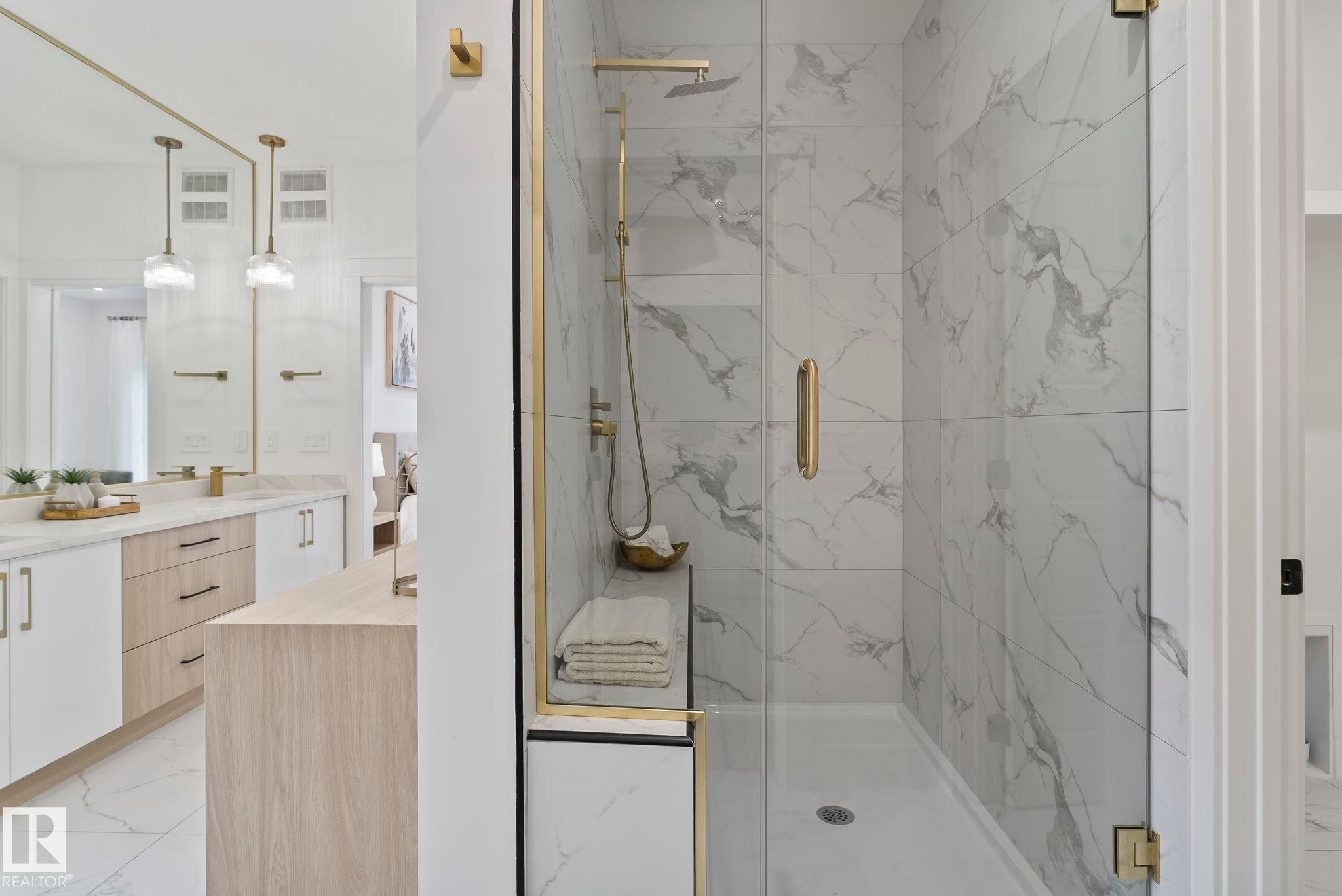 Spacious shower with large format marble-look tile, glass enclosure with gold-tone hardware, and built-in bench - 13152 187 Avenue, Edmonton, AB